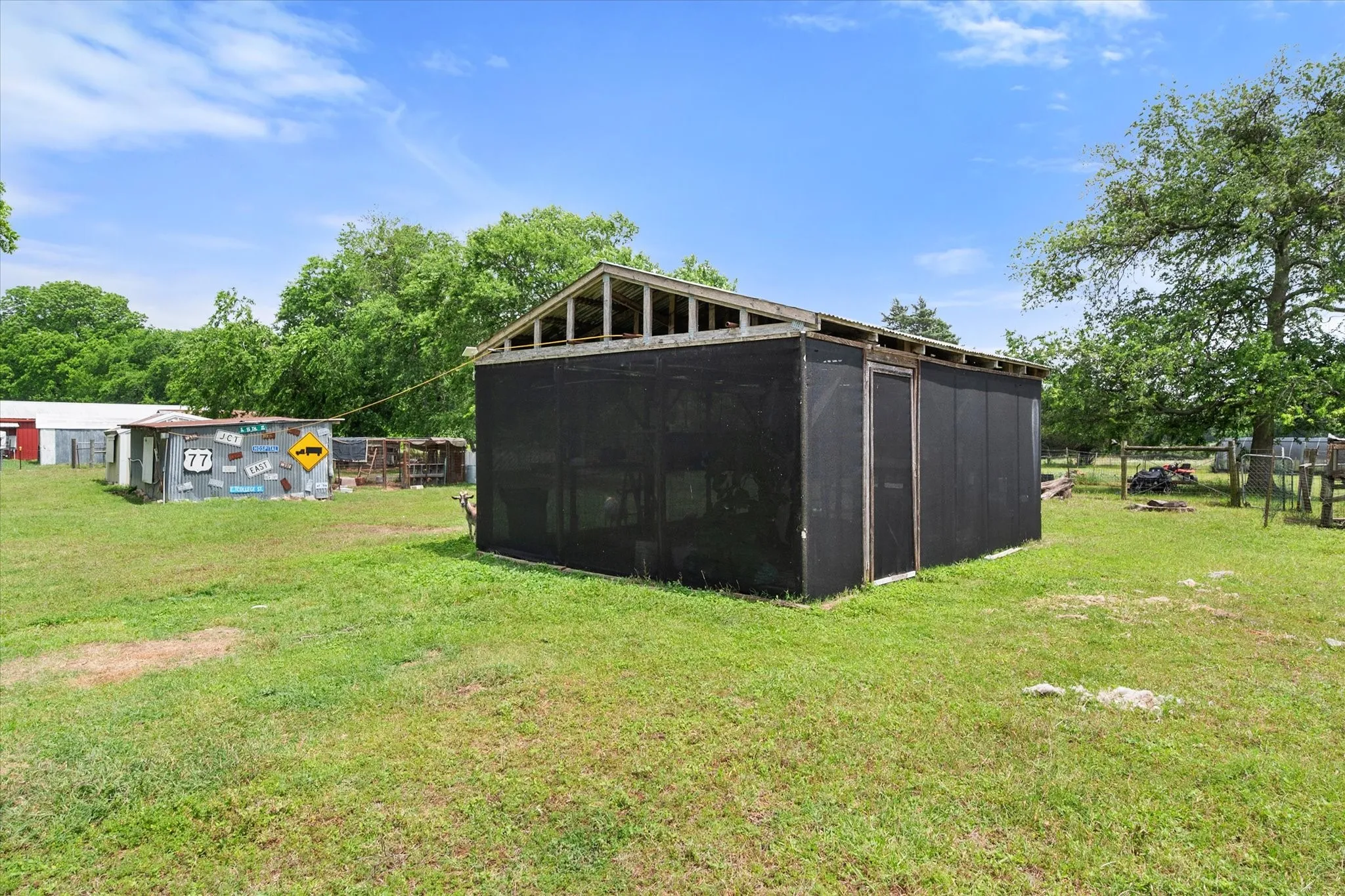 Spacious outdoor structure with screened walls and exposed rafter ends, set on a grassed area