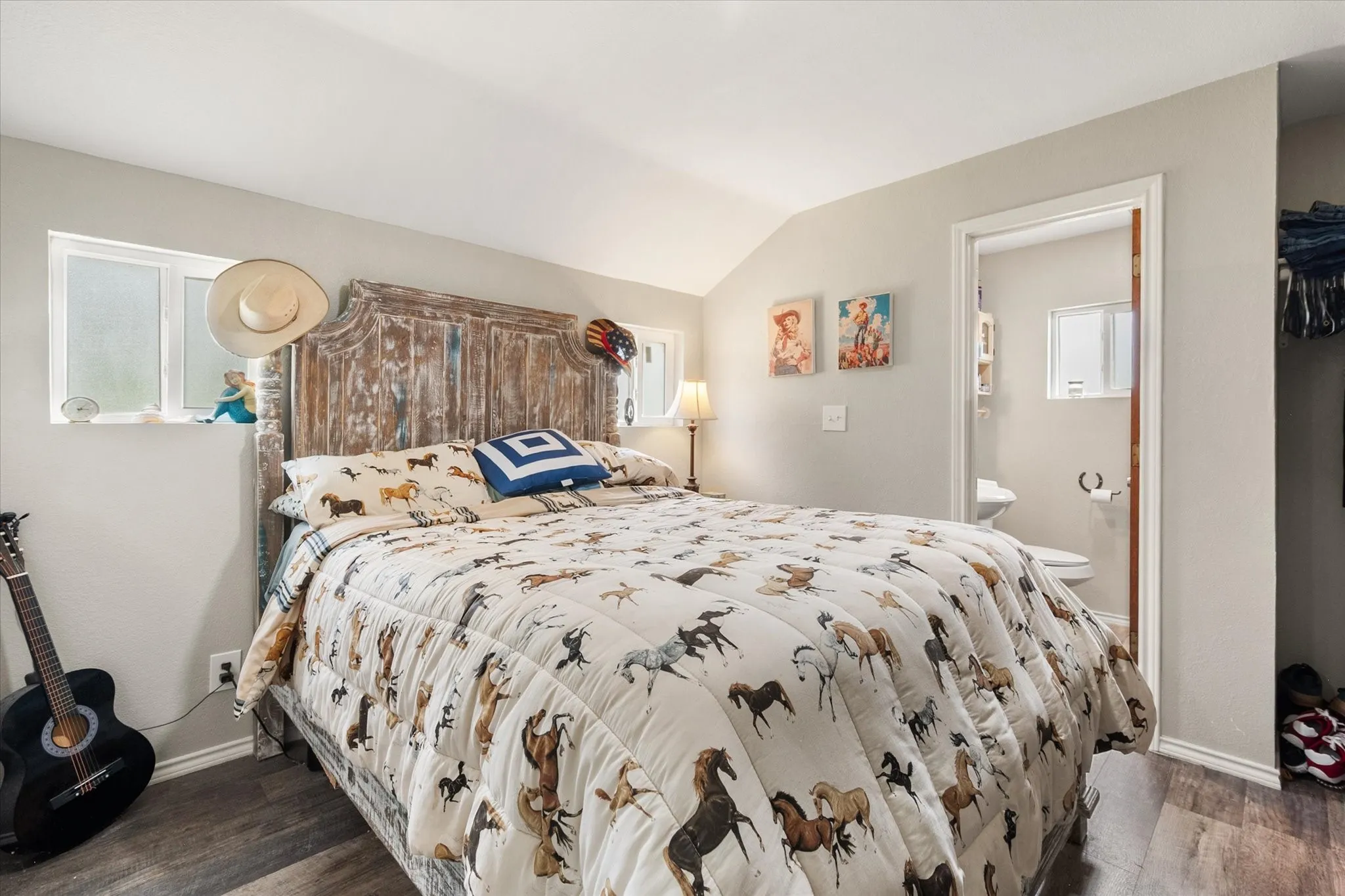Bedroom featuring wood-finish flooring, a textured wood headboard, and a vaulted ceiling
