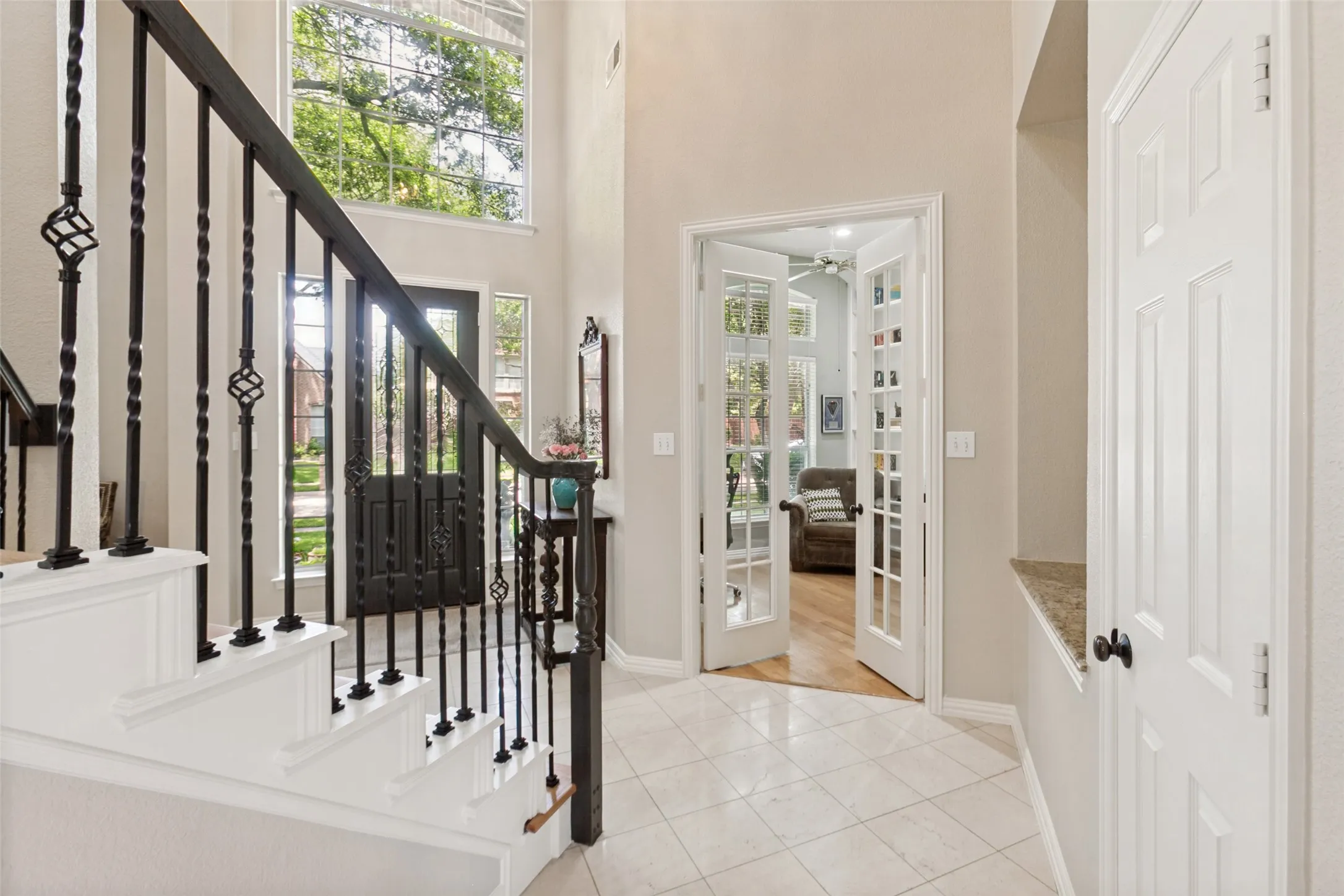 Entryway featuring a grand staircase with wrought iron balusters and white risers