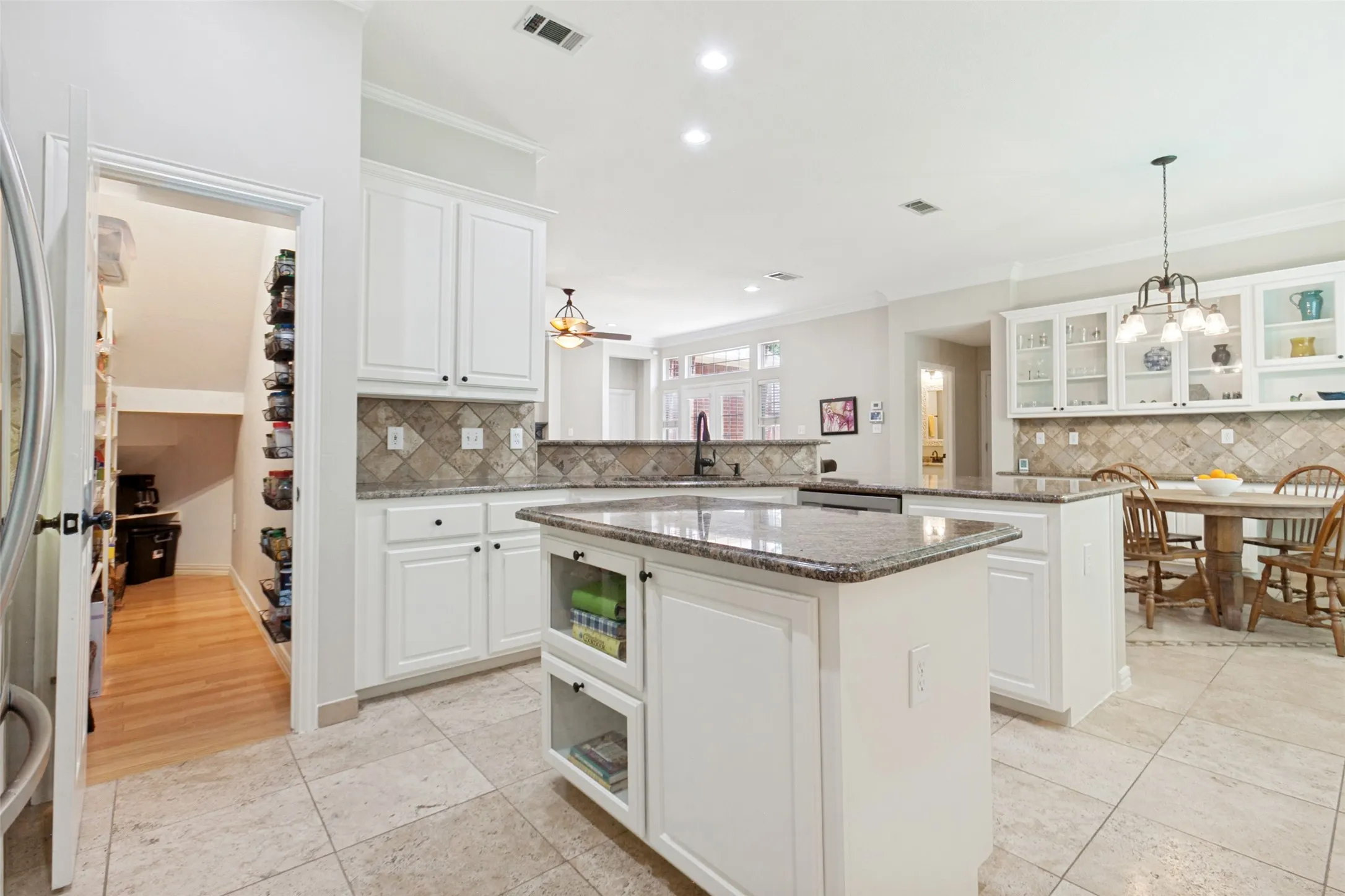 Spacious kitchen featuring an island, white cabinetry, granite countertops, and tile flooring