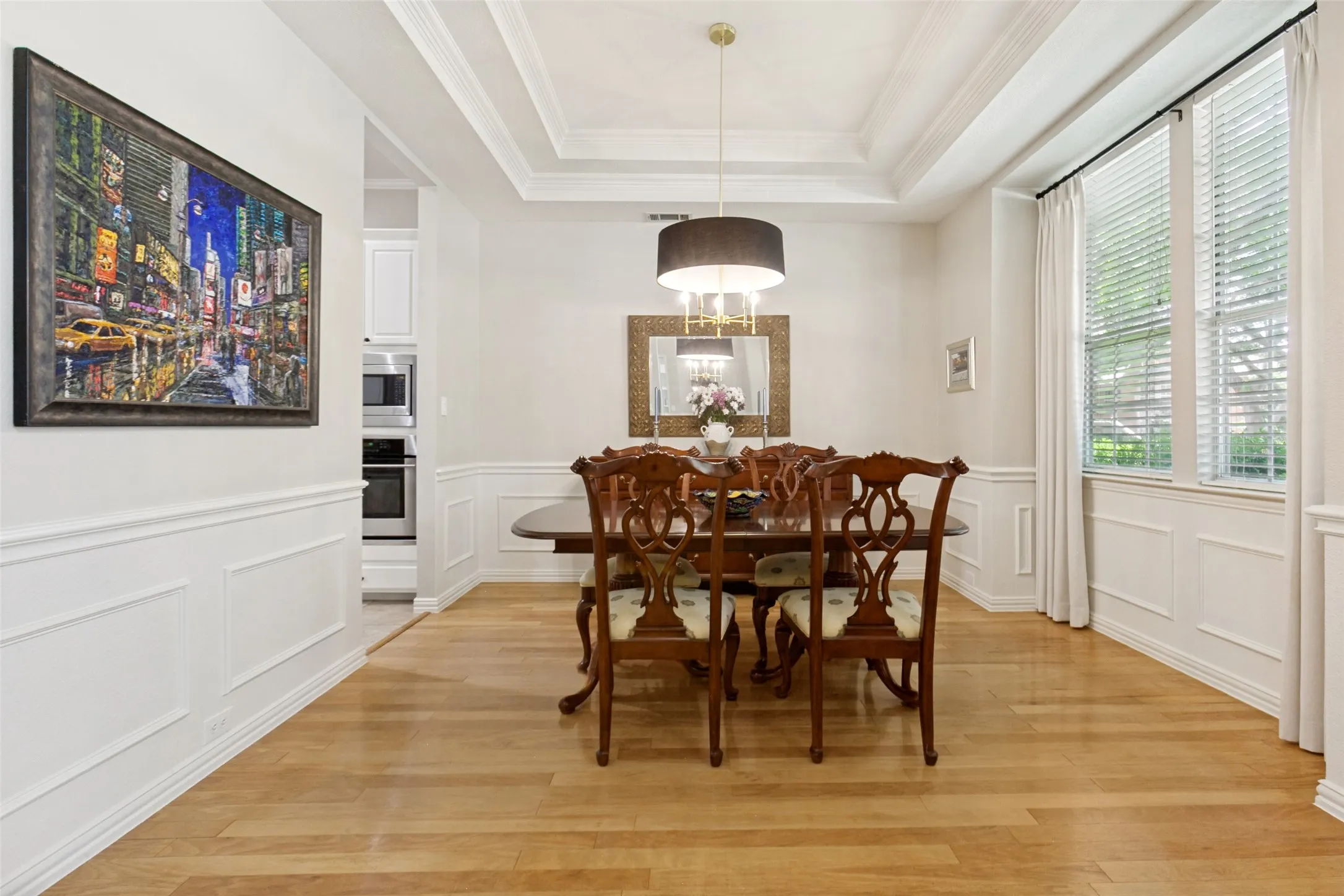 Dining area featuring wood-finish flooring, wainscoting, and a coffered ceiling