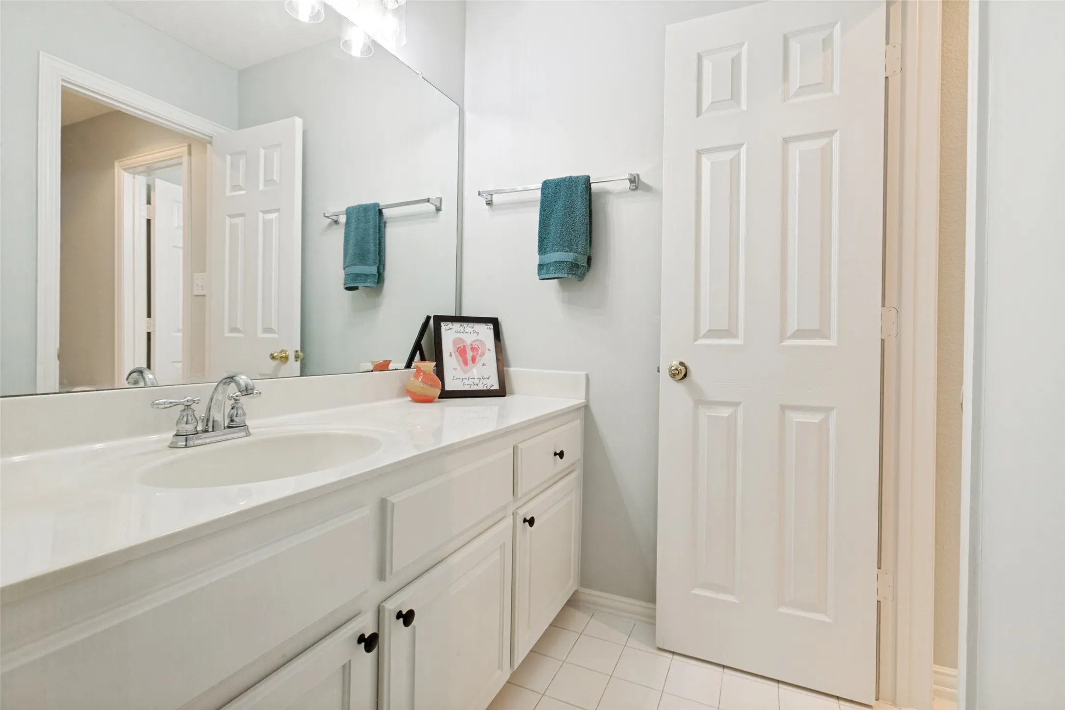 Jack and Jill bathroom with white vanity, a built-in sink, chrome faucet and updated light fixture
