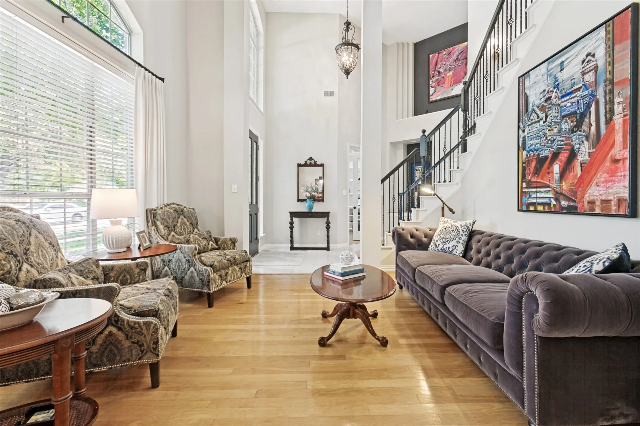 Two-story foyer with hardwood flooring, a prominent staircase featuring black wrought iron spindles, and a large arched window