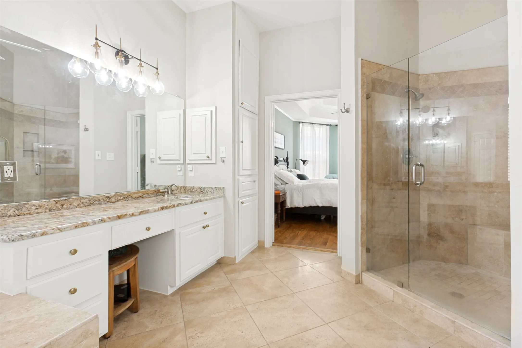 Bathroom featuring a glass-enclosed shower, dual vanity with a stone countertop, built-in cabinetry, and tile flooring