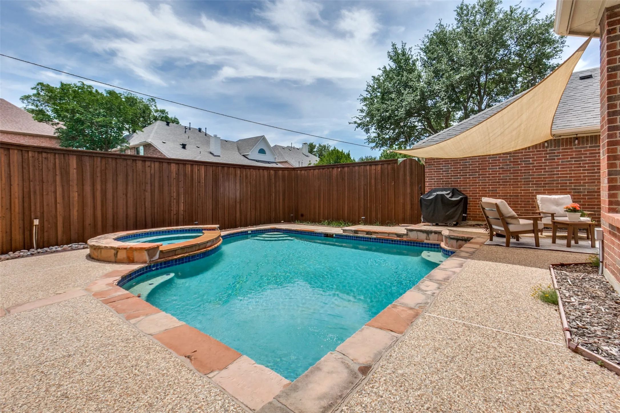 Backyard boasts a Gunite pool with integrated spa, exposed aggregate concrete decking, and board-on-board fence