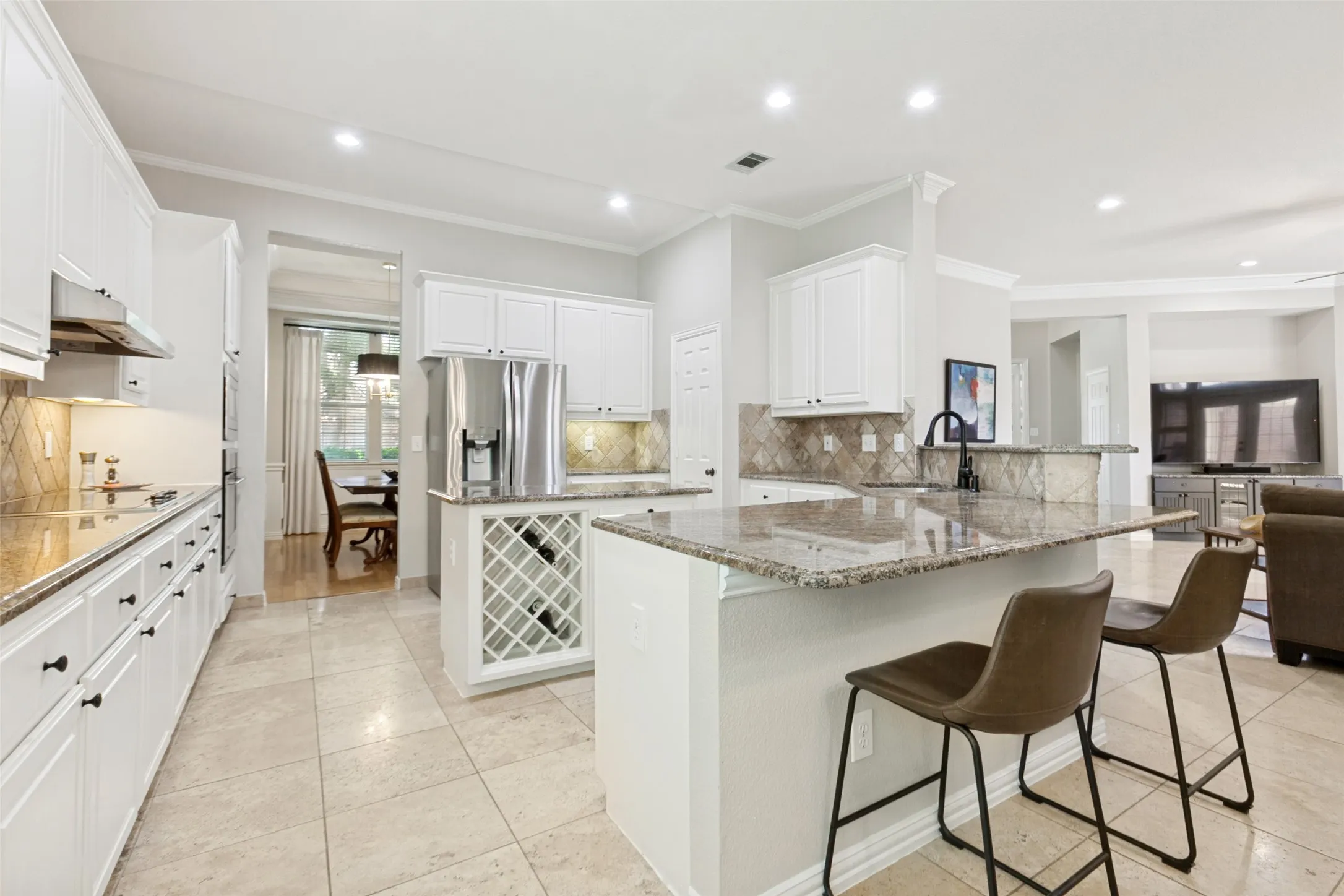 Kitchen featuring white cabinetry, granite countertops, stainless steel appliances, a built-in wine rack, and tile flooring