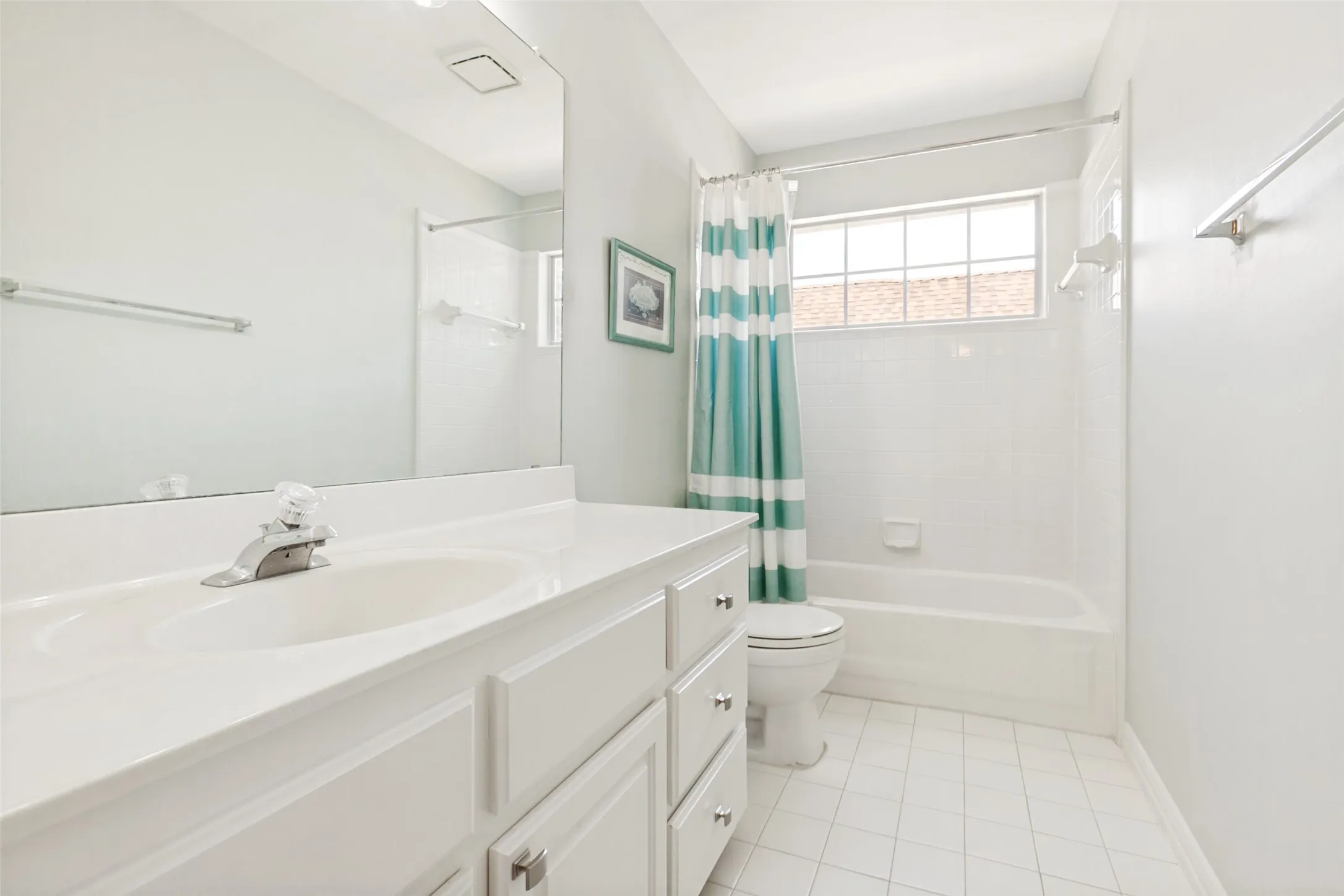 Separate bathroom featuring a white vanity with integrated sink, a large wall-mounted mirror, a bathtub with white subway tile surround, a window, white tile flooring and updated light fixture