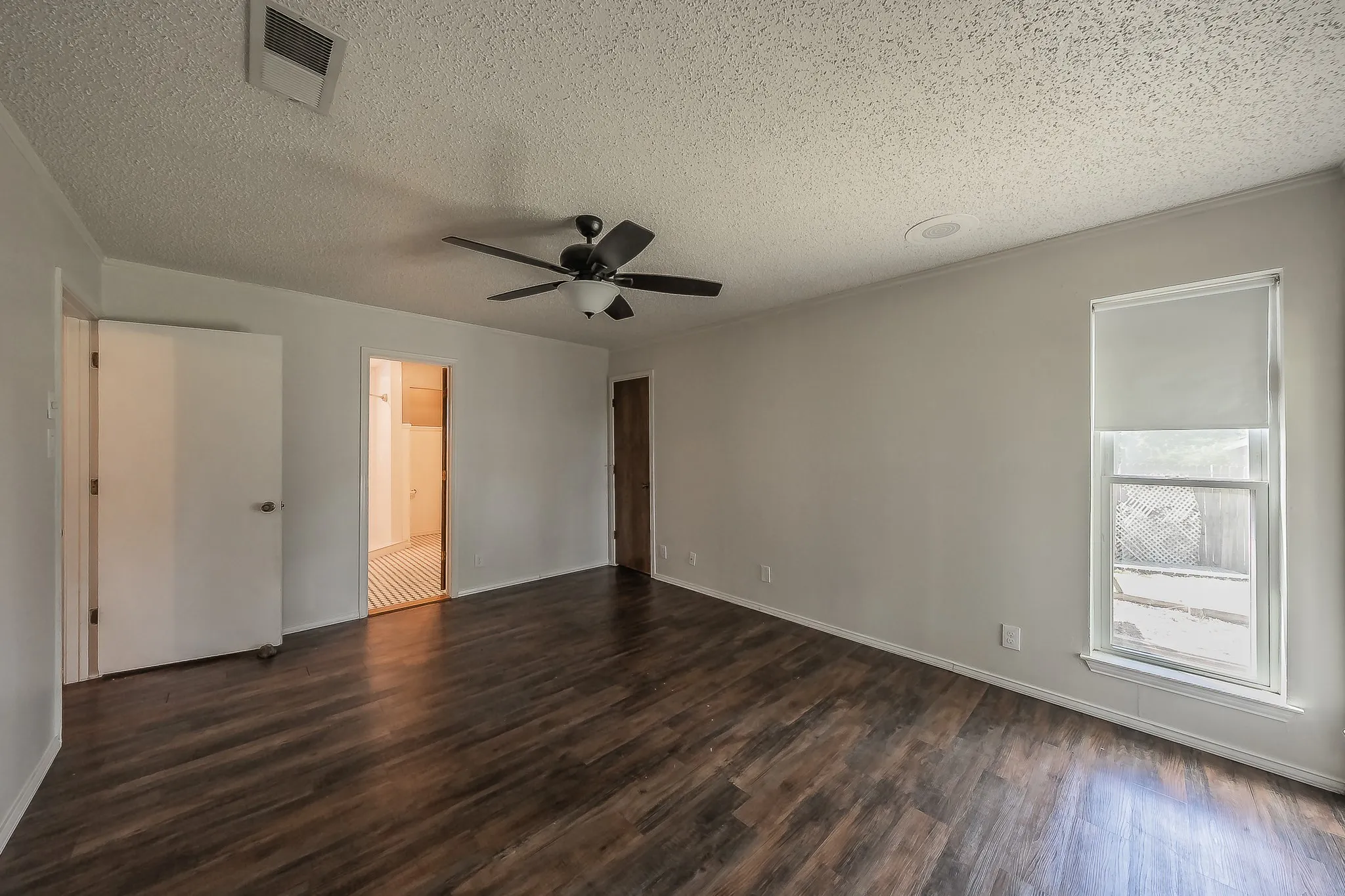 Spacious room featuring wood-finish flooring, a ceiling fan with integrated lighting, and neutral wall tones