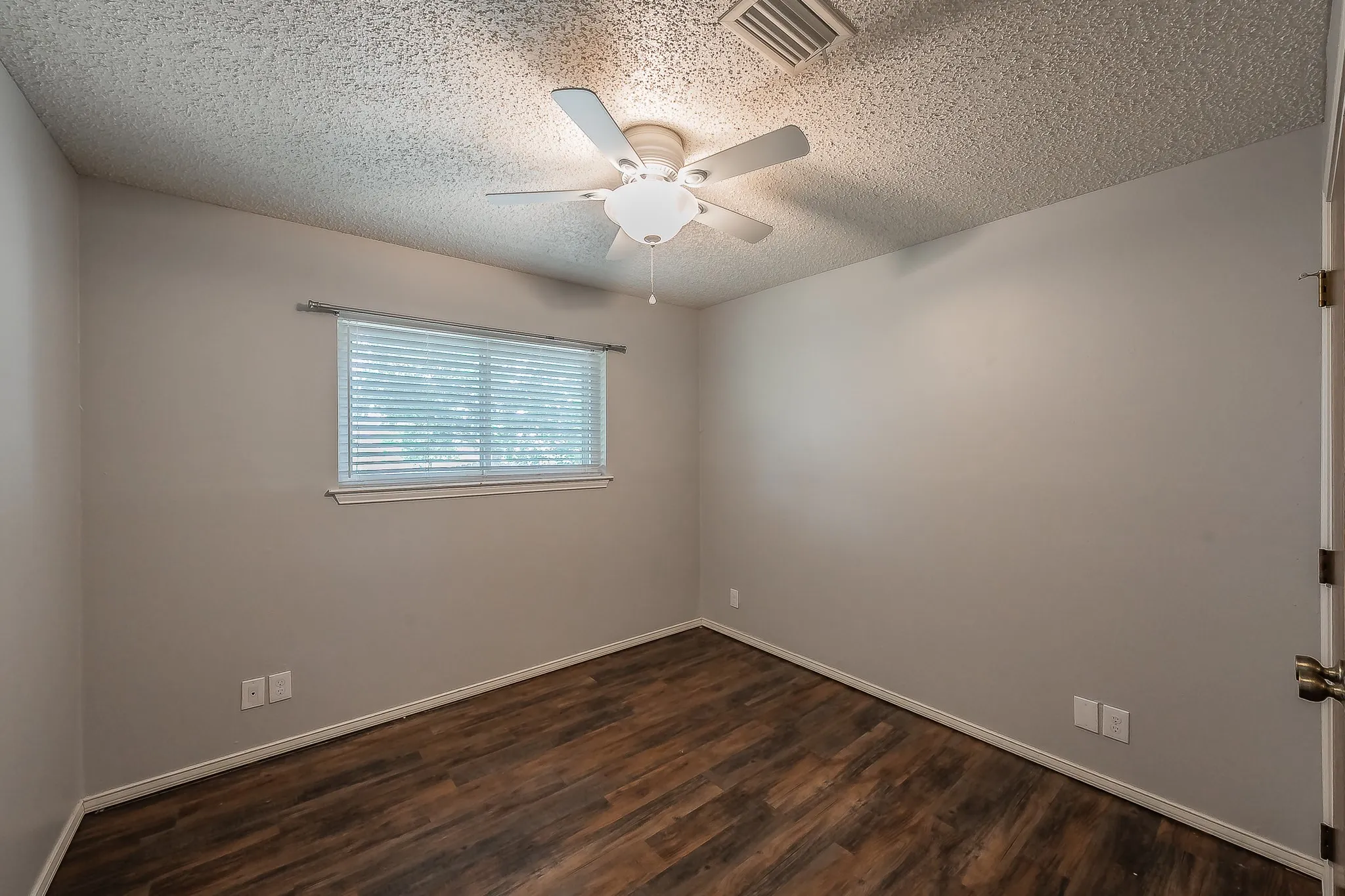 Room with wood-finish flooring, neutral wall paint, and a textured ceiling