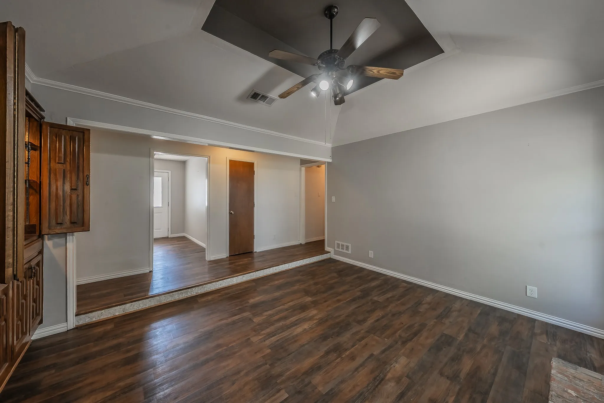 Spacious interior featuring wood-finish flooring, a recessed ceiling with a ceiling fan, and light gray wall finishes