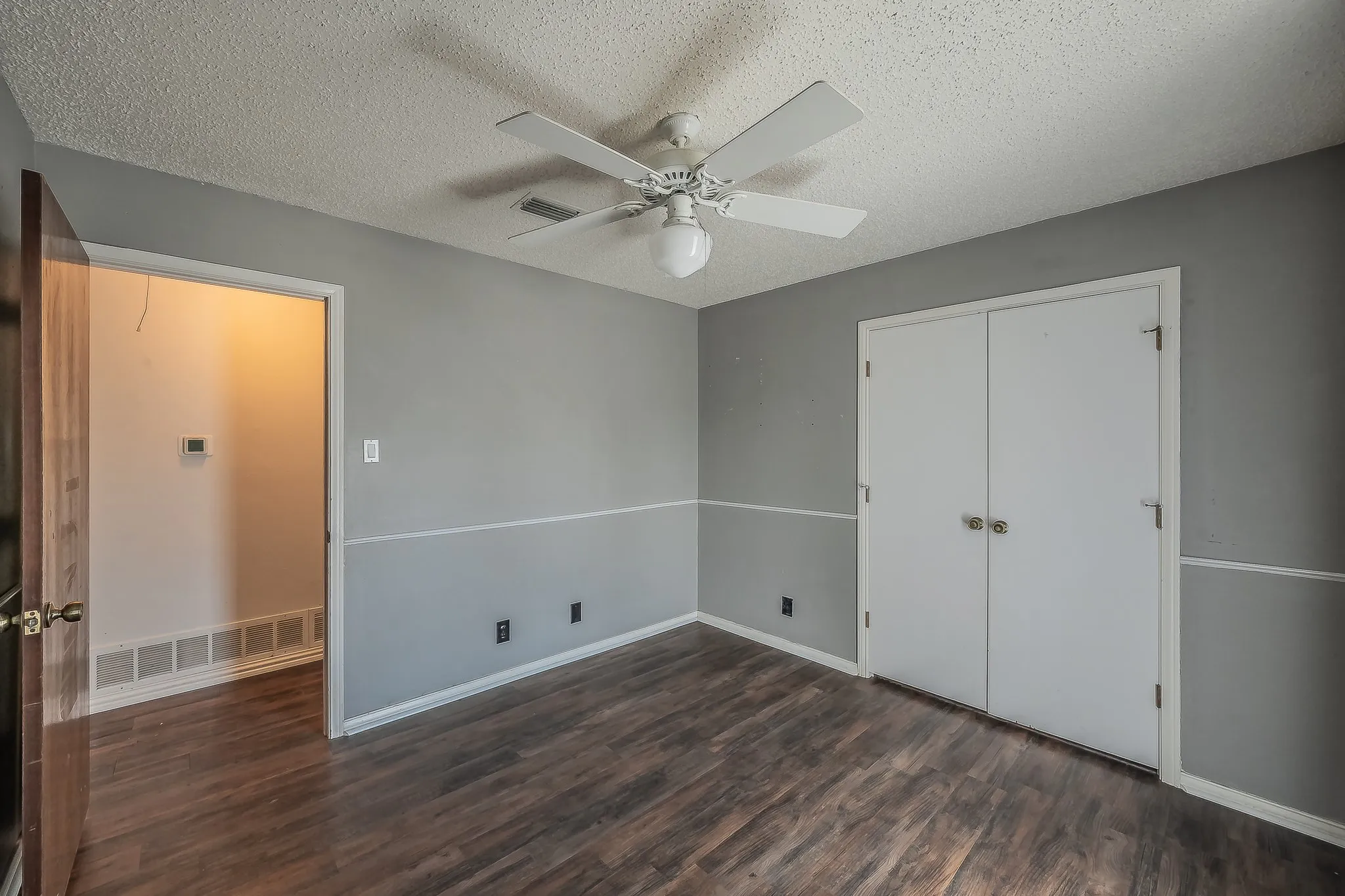 Room featuring wood-finish flooring, two-tone painted walls, and a ceiling fan with integrated lighting