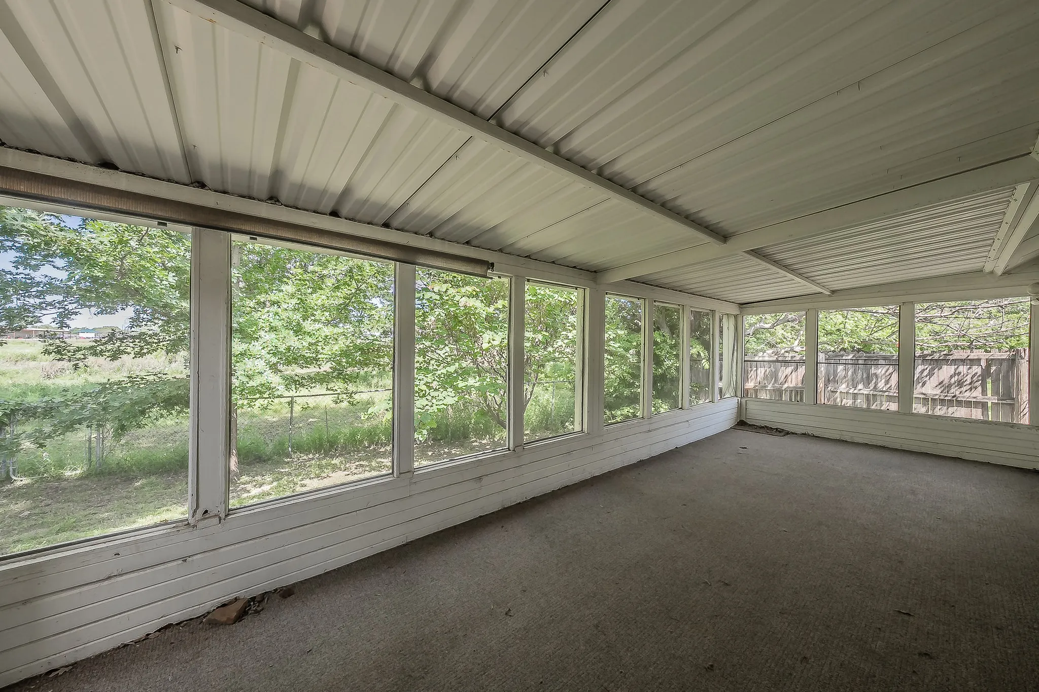 Enclosed patio featuring a corrugated metal ceiling and multiple window panels