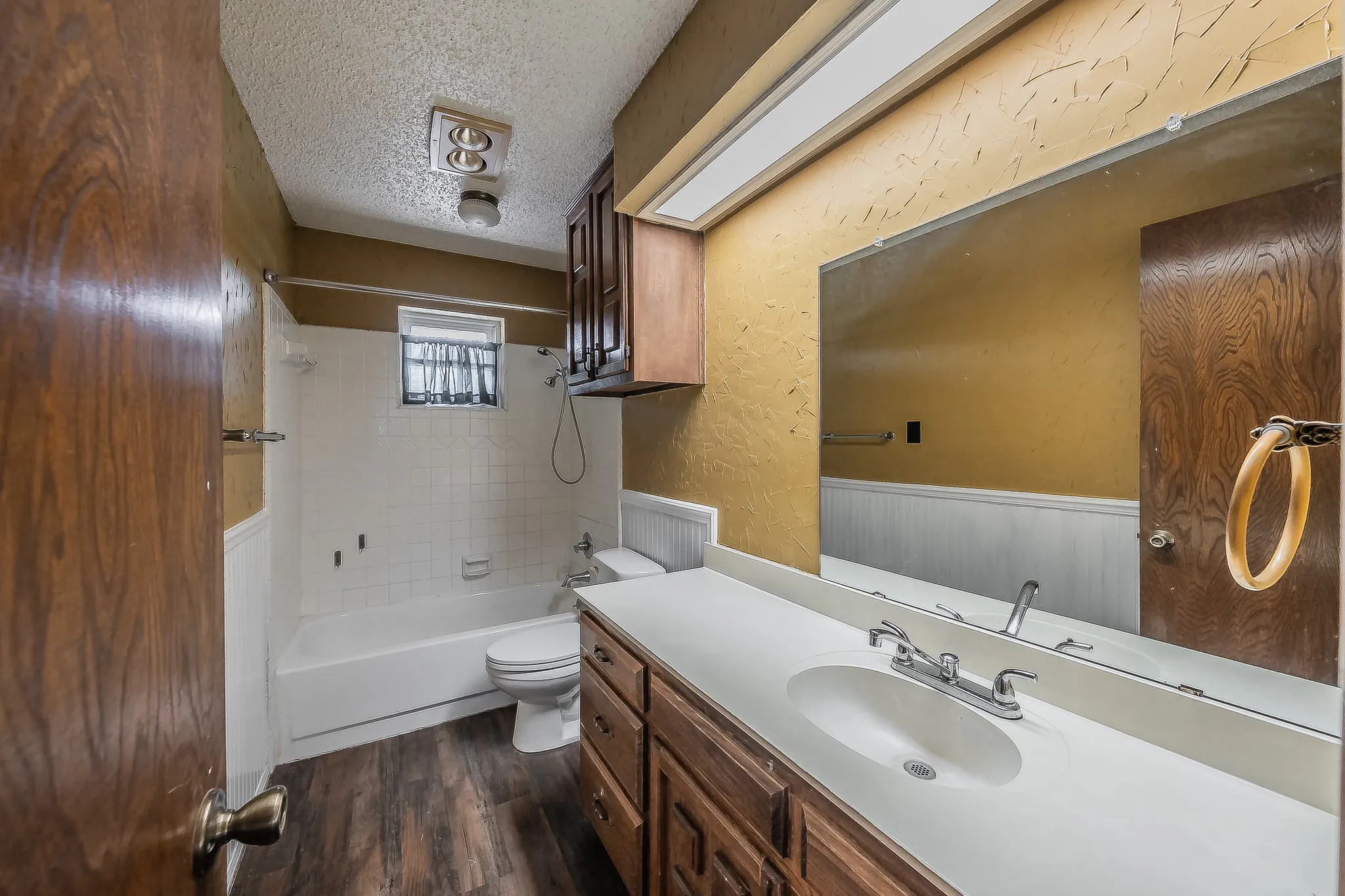 Bathroom featuring a single vanity with an integrated sink, a large wall-mounted mirror, and wood-finish cabinetry