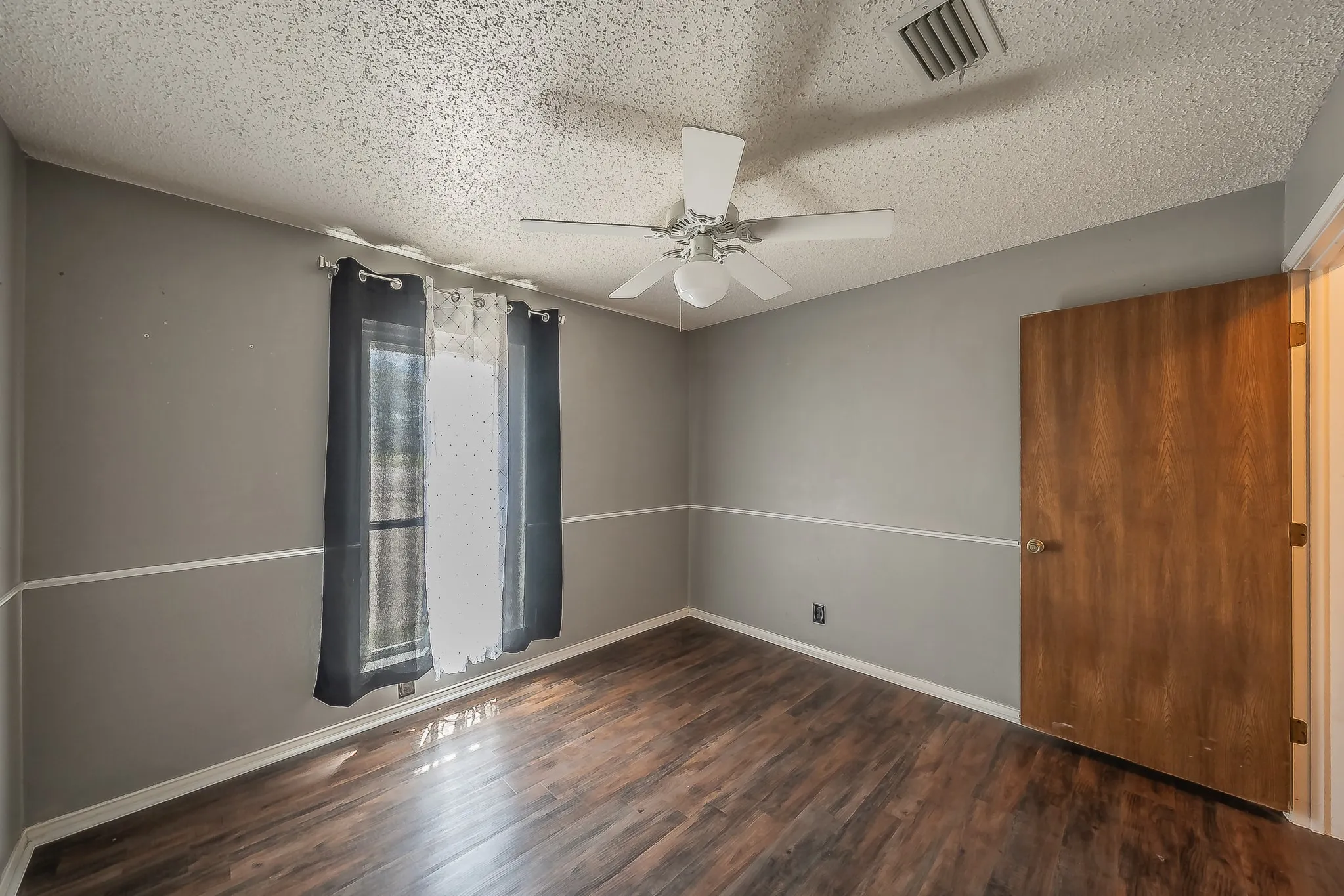 Room featuring wood-finish flooring, a ceiling fan, and a light-colored door