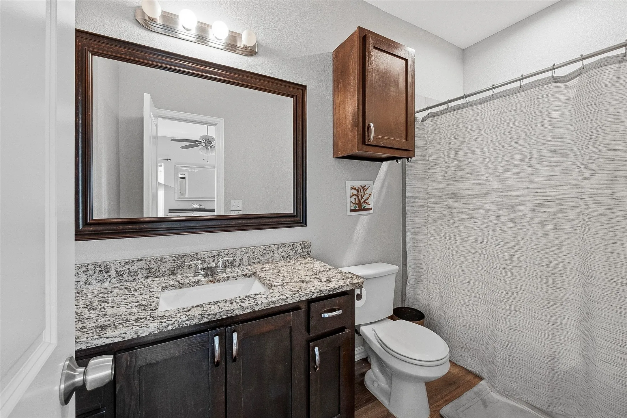Bathroom vanity featuring a speckled countertop, undermount sink, and dark wood-finish cabinetry with silver hardware