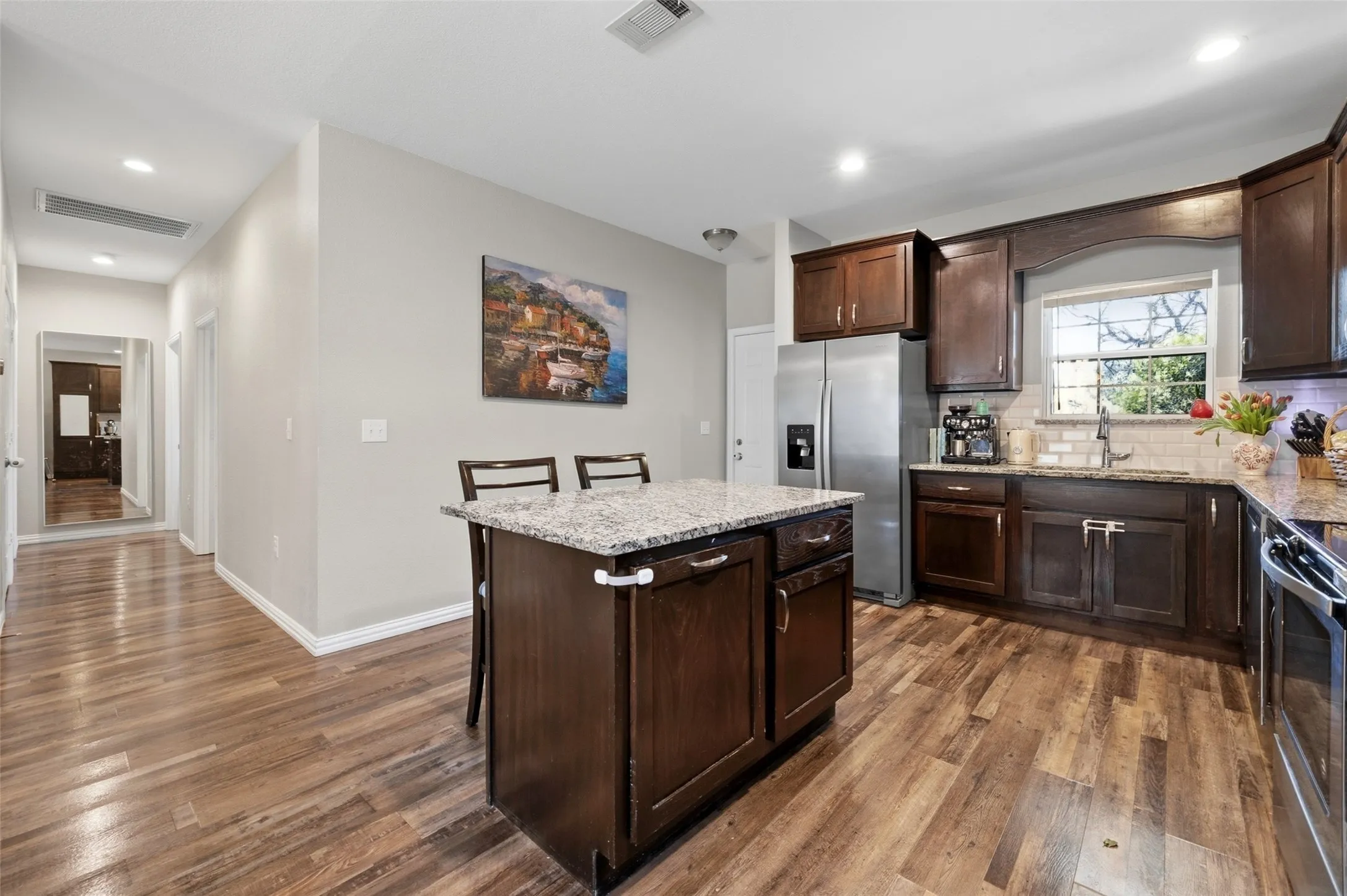 Kitchen featuring wood-finish flooring, dark wood cabinetry, and granite countertops