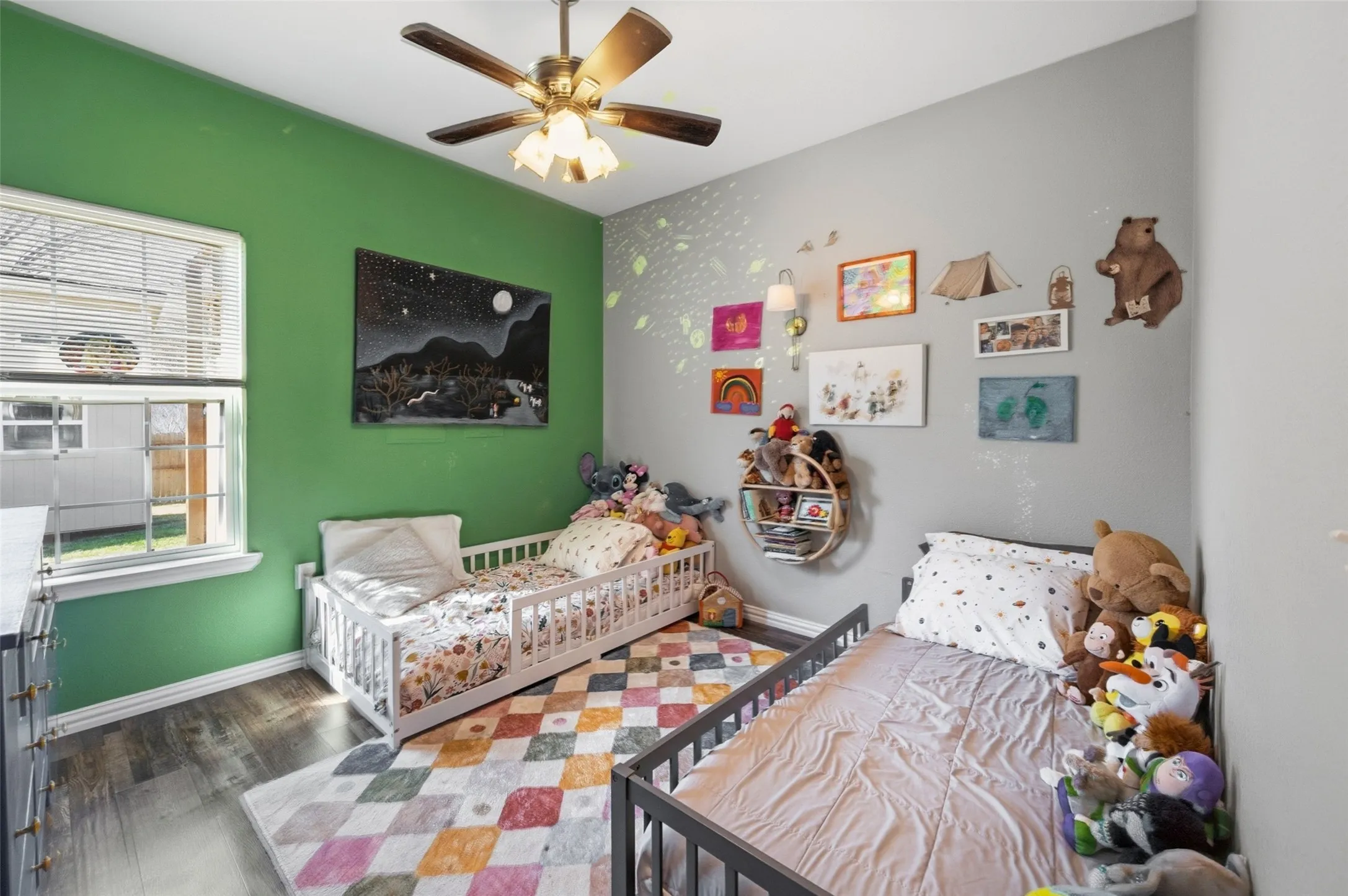 Room featuring two-tone painted walls, wood-finish flooring, a ceiling fan with integrated lighting, and a window with blinds