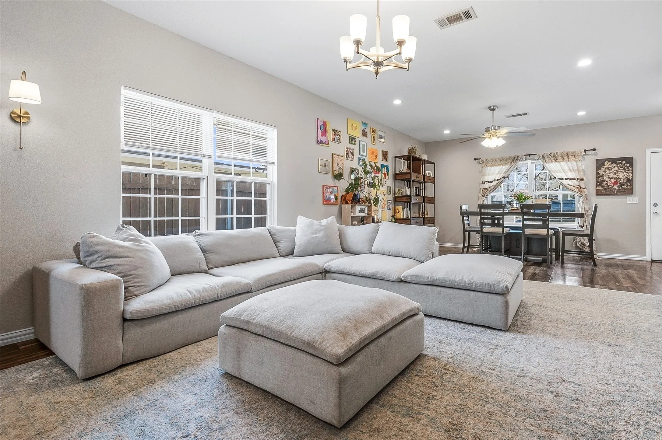 Spacious living area featuring light-toned walls, wood-finish flooring, and a dining space with a ceiling fan