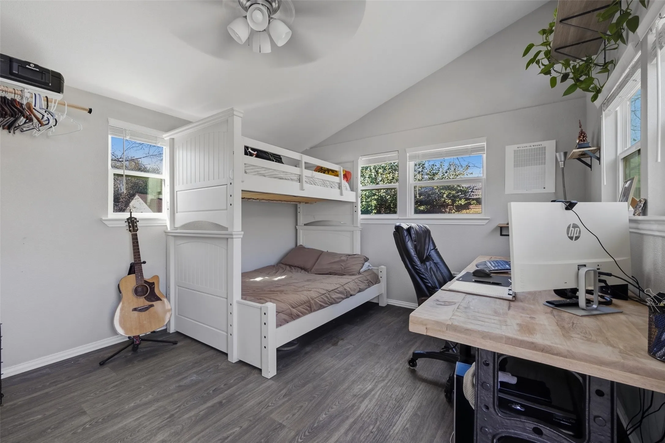 Room featuring wood-finish flooring, multiple windows, a ceiling fan, and a built-in bunk bed