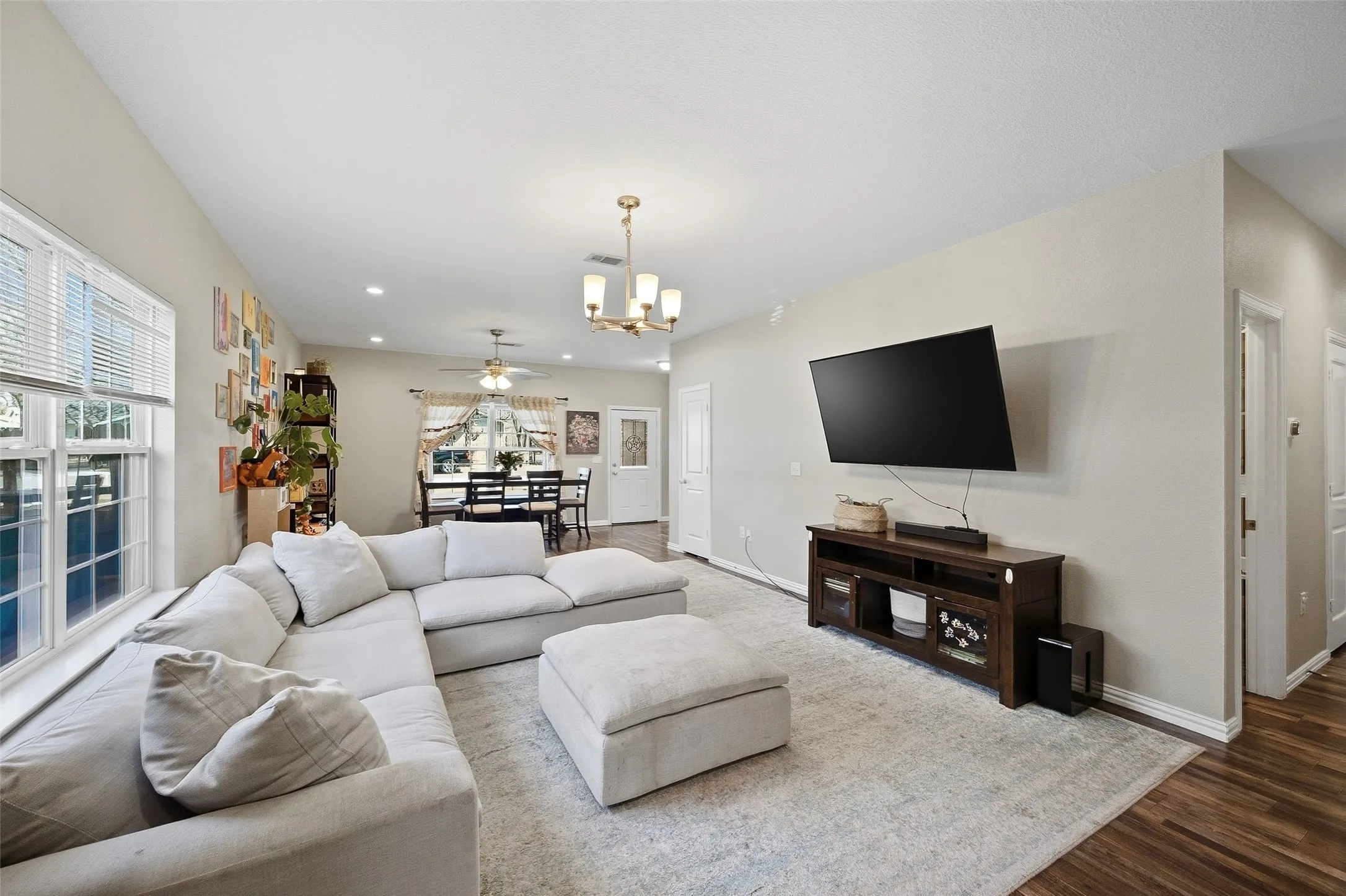 Open-concept living area featuring light-colored walls and wood-finish flooring