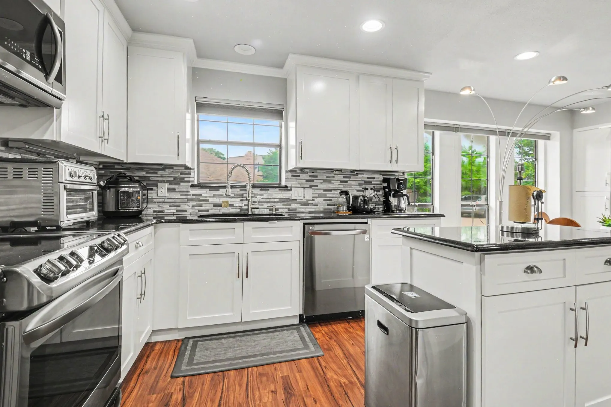Modern kitchen featuring white cabinetry, dark countertops, and a mosaic tile backsplash