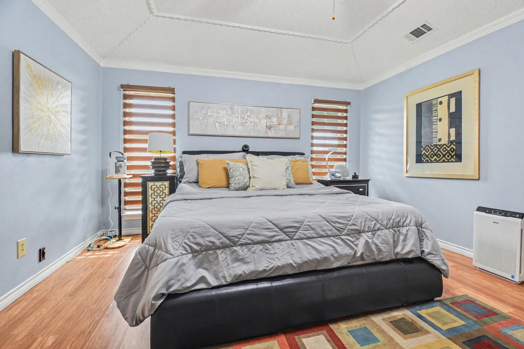 Vaulted ceiling with decorative trim, wood-finish flooring, and light blue walls