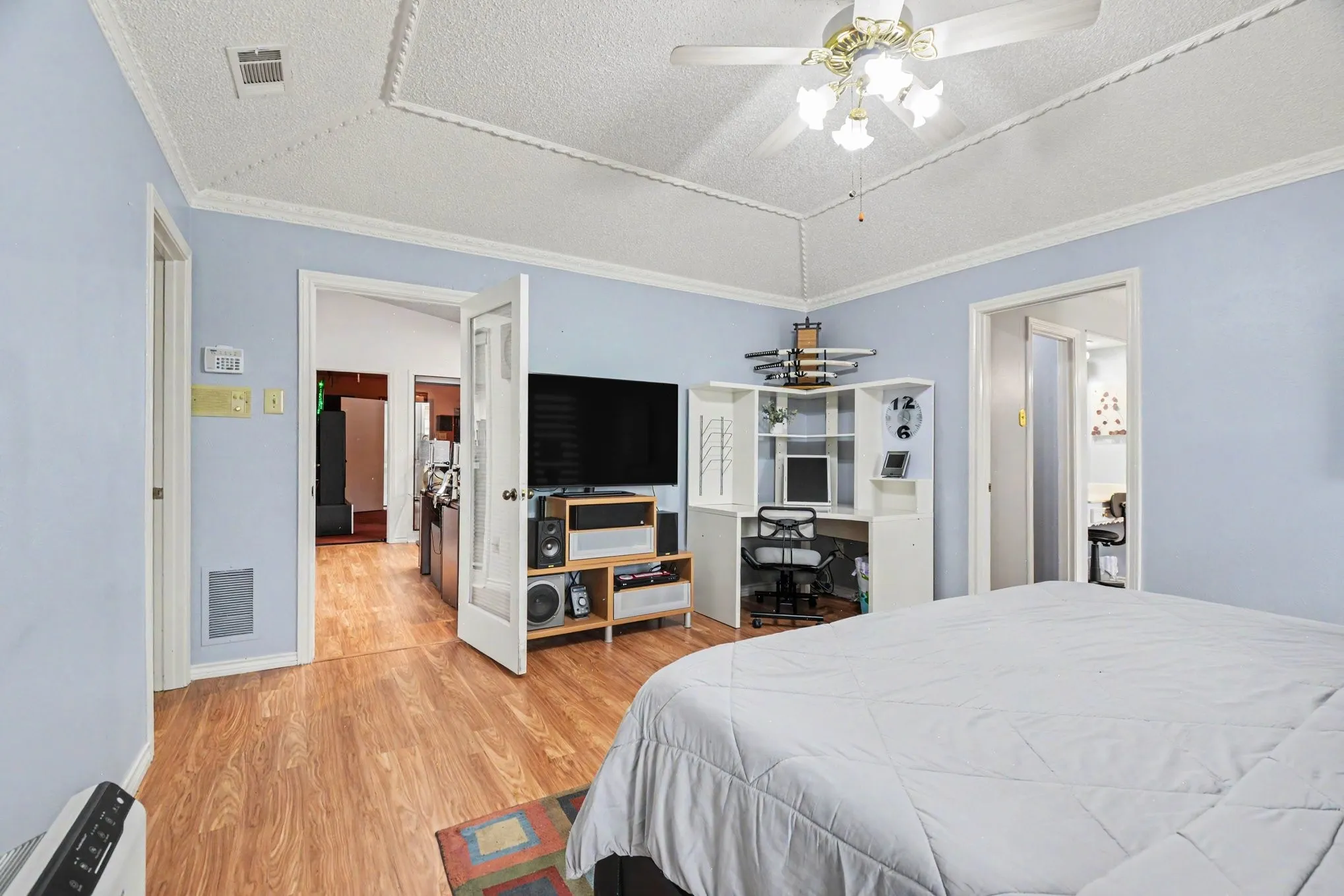 Spacious room featuring wood-finish flooring and a tray ceiling with crown molding