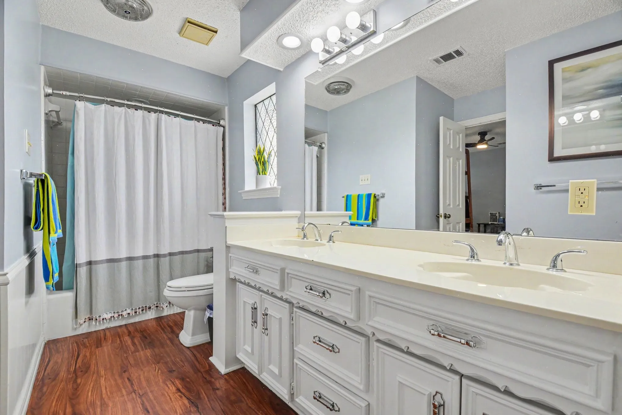 Bathroom featuring a double vanity with integrated sinks, white cabinetry, and polished chrome fixtures