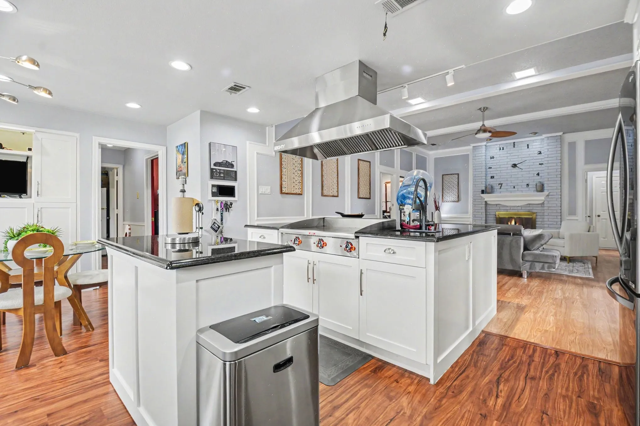 Kitchen featuring a large stainless steel commercial-style range hood and a dual-island layout with dark countertops