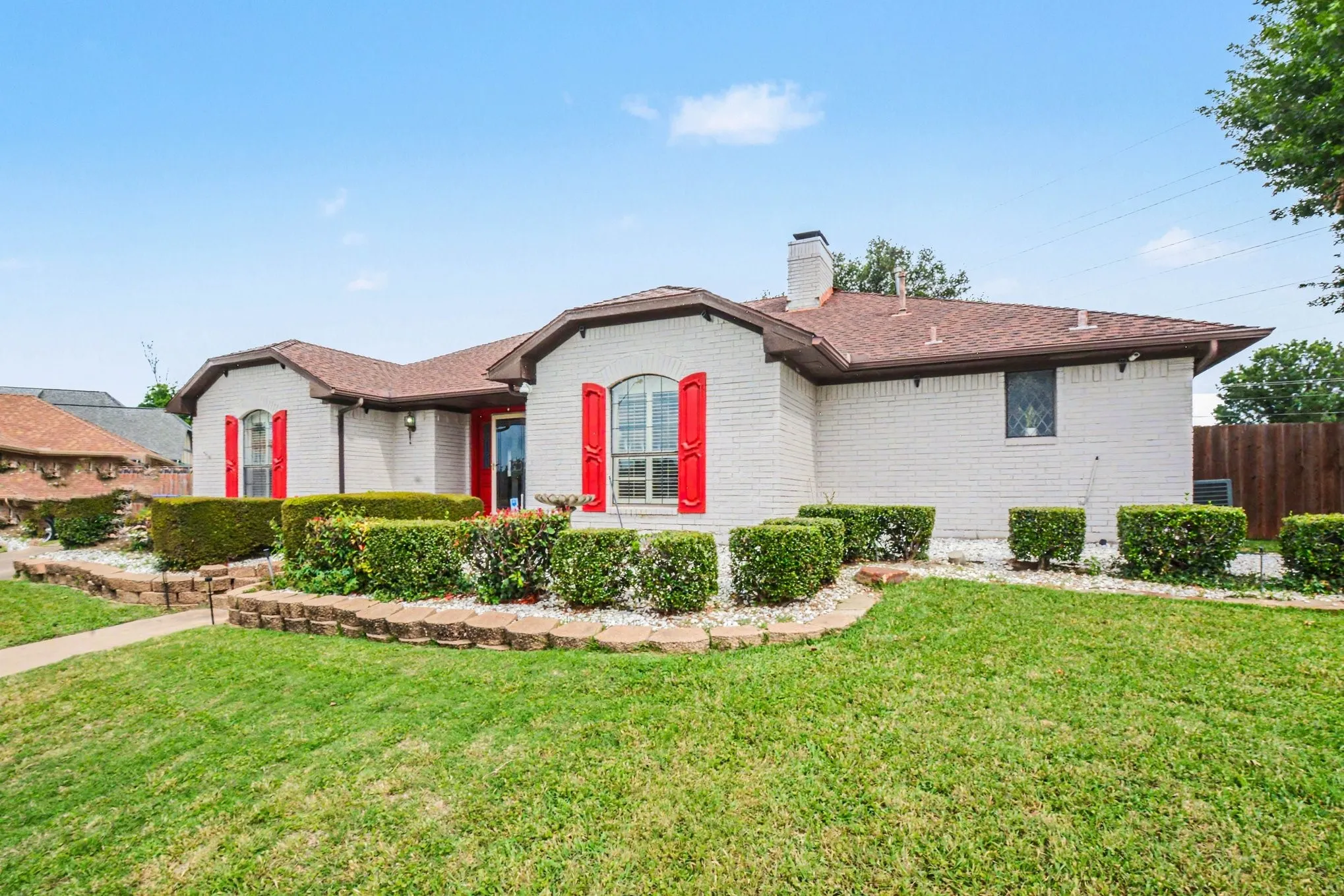 White brick exterior with red shutters and a prominent red front door