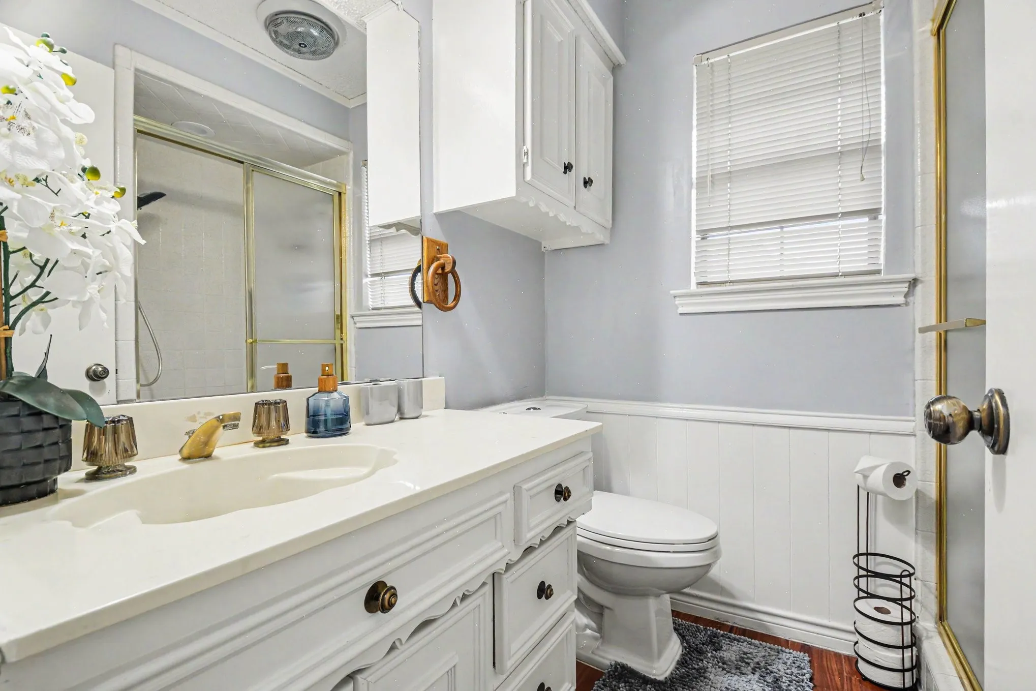 Guest Bathroom White vanity with integrated sink, gold-tone faucet, and brass hardware