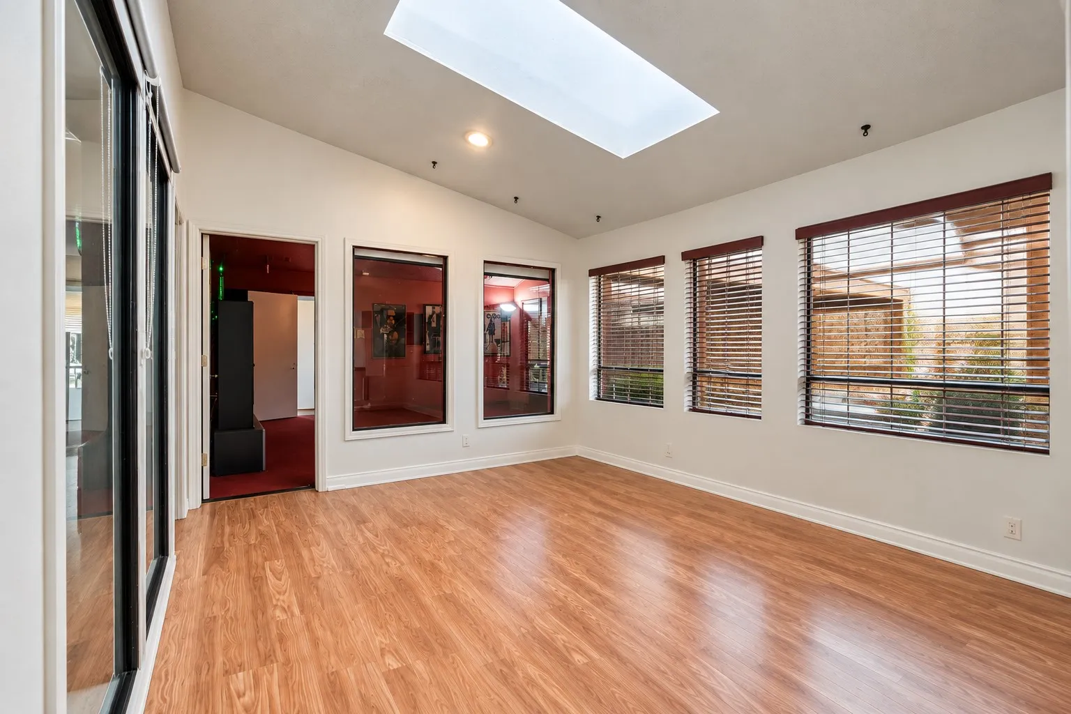 Wood-finish flooring, multiple windows with blinds, a large skylight, and recessed lighting