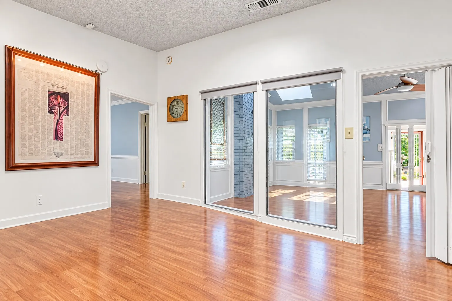 Wood-finish flooring throughout, sliding glass doors, interior transom windows, skylight, and white paneled walls