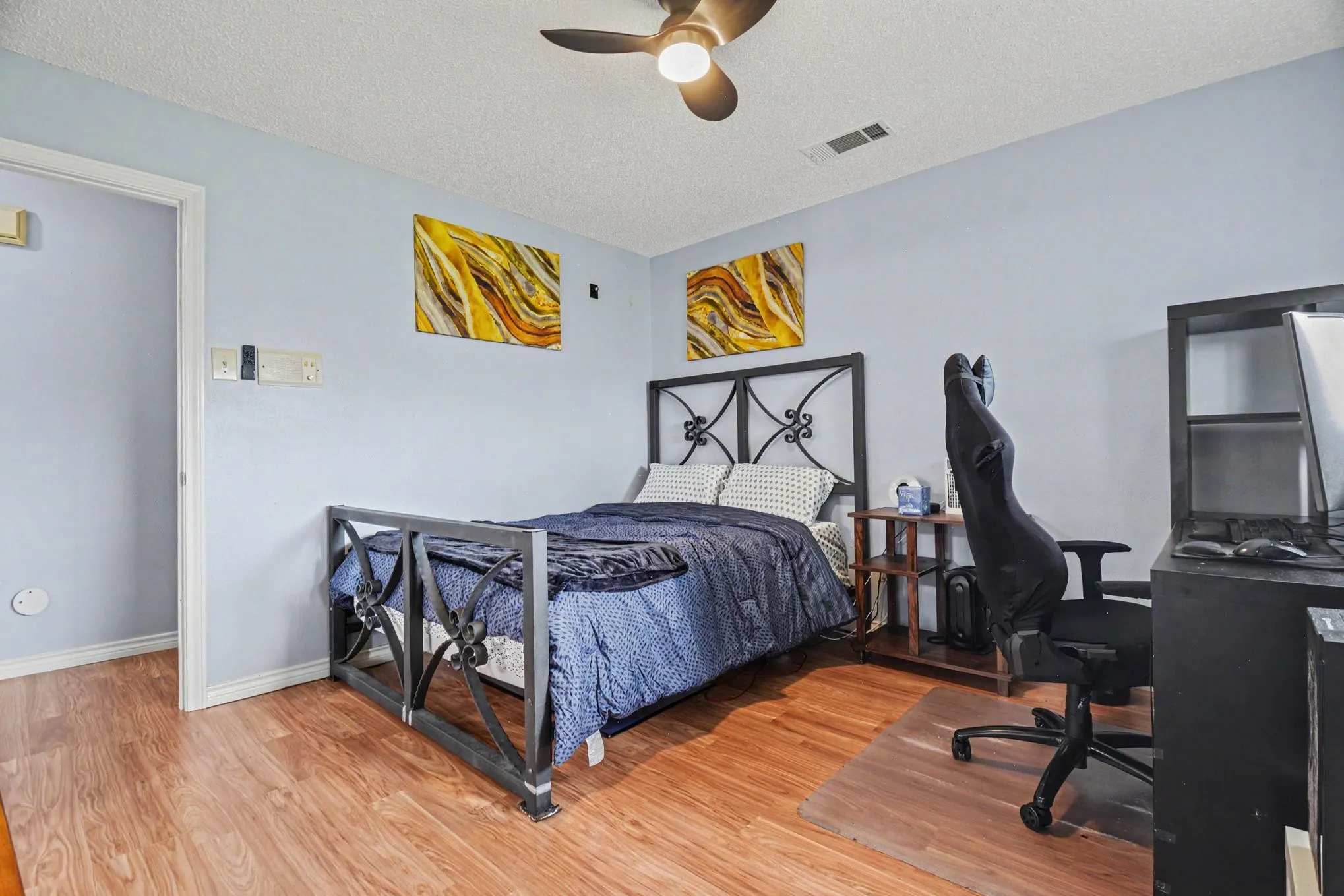 Room featuring wood-finish flooring, a ceiling fan, and light blue wall tones