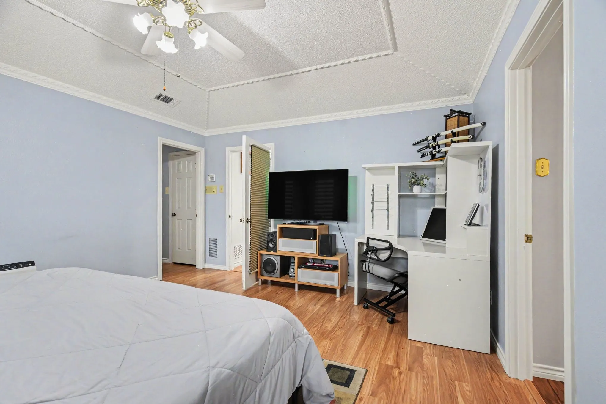 Bedroom featuring wood-finish flooring, light blue walls, and white crown molding