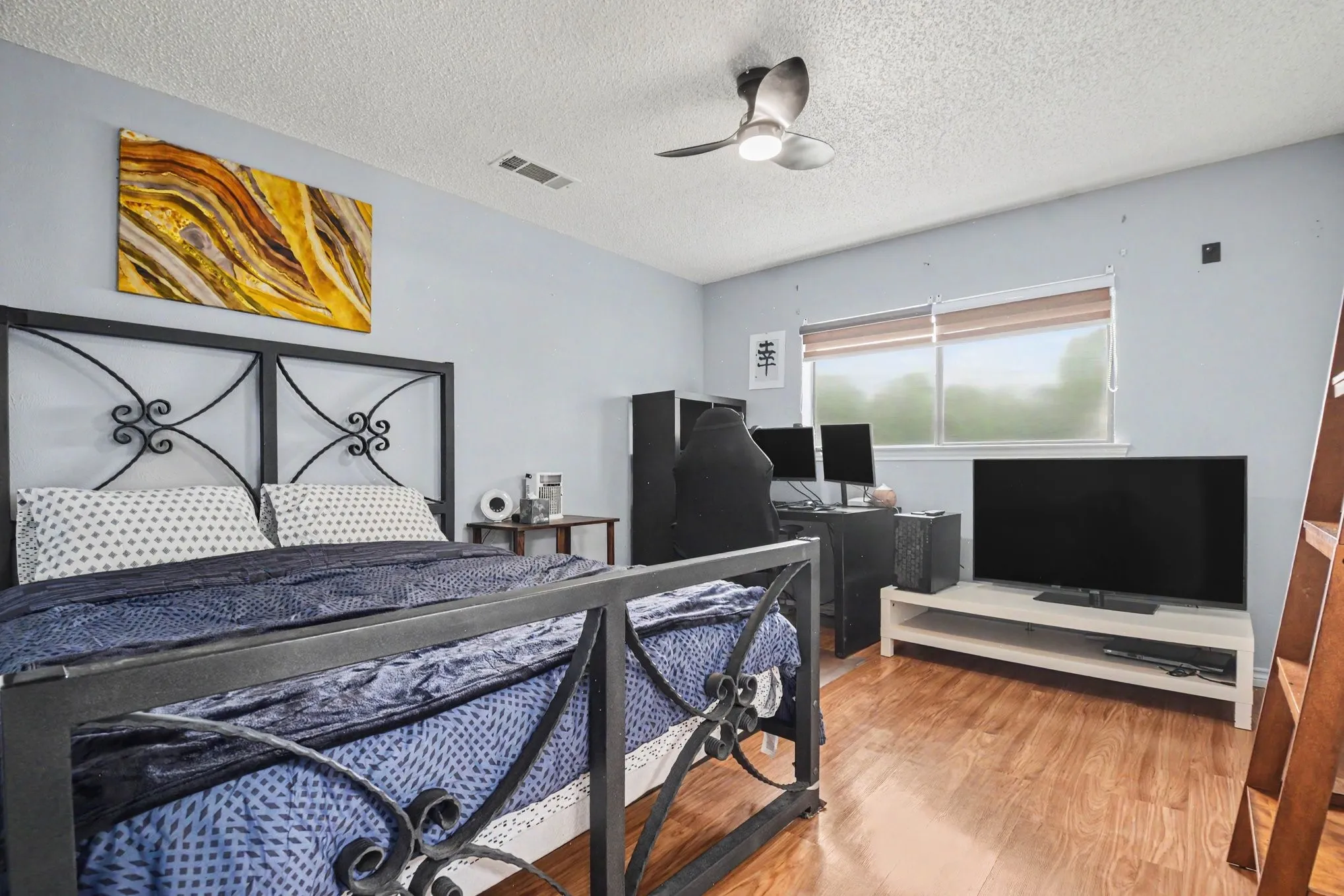 Bedroom featuring wood-finish flooring, light blue walls, and a ceiling fan