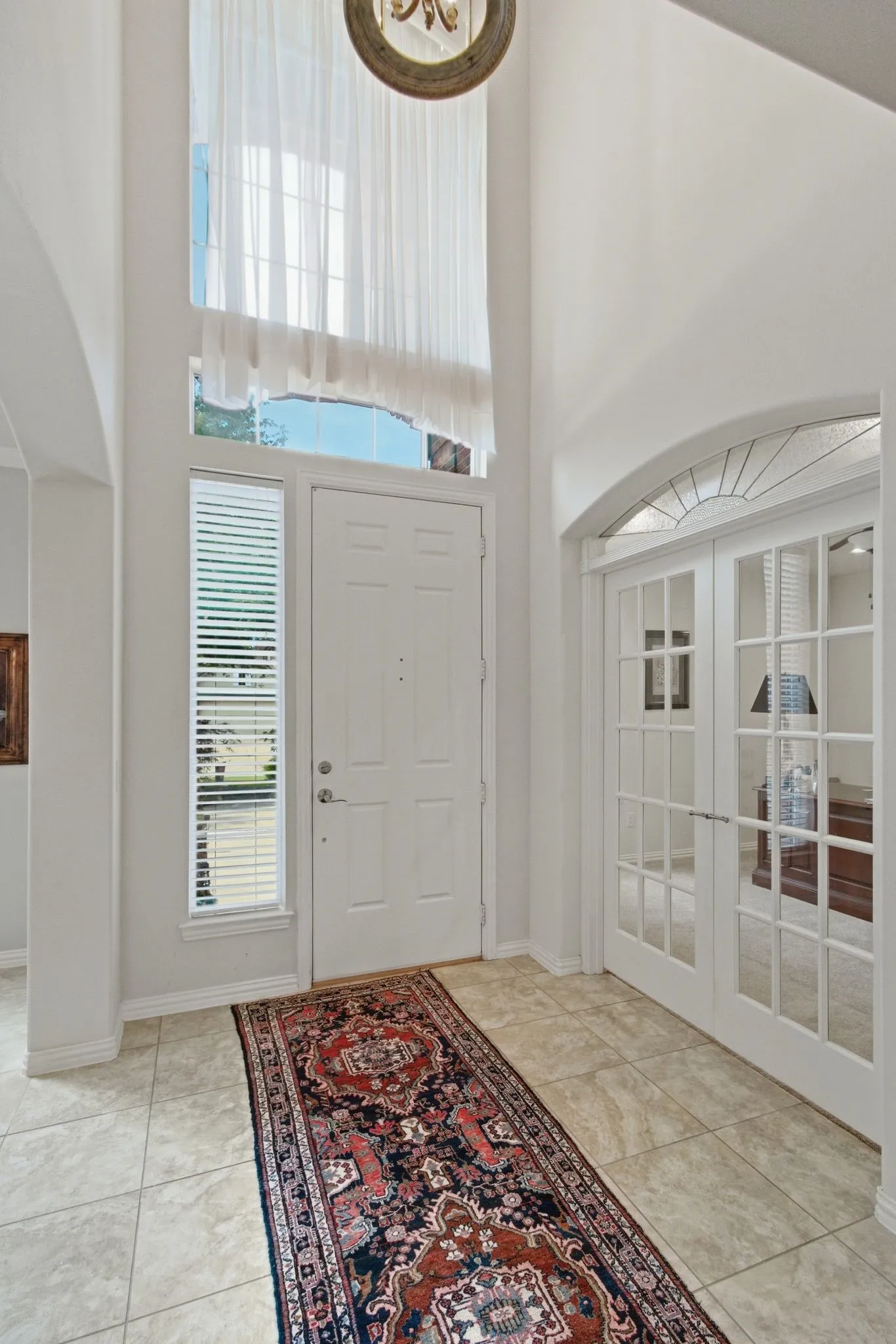 Two-story foyer featuring an arched entryway, transom window, and tile flooring