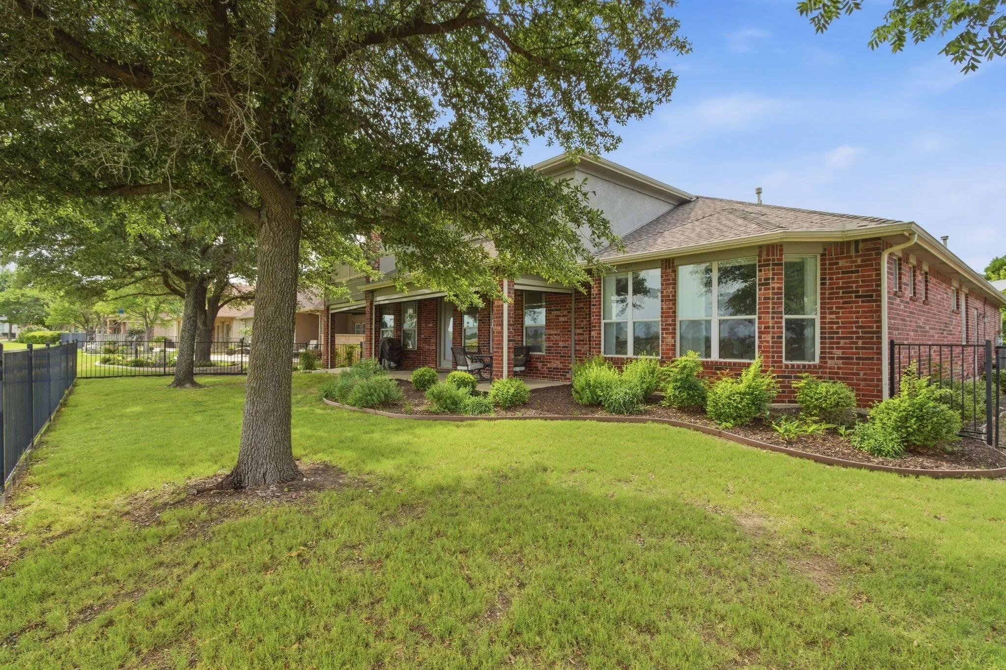 Brick two-story residence featuring a two-car and a half car garage, concrete driveway, and a front yard with mature trees