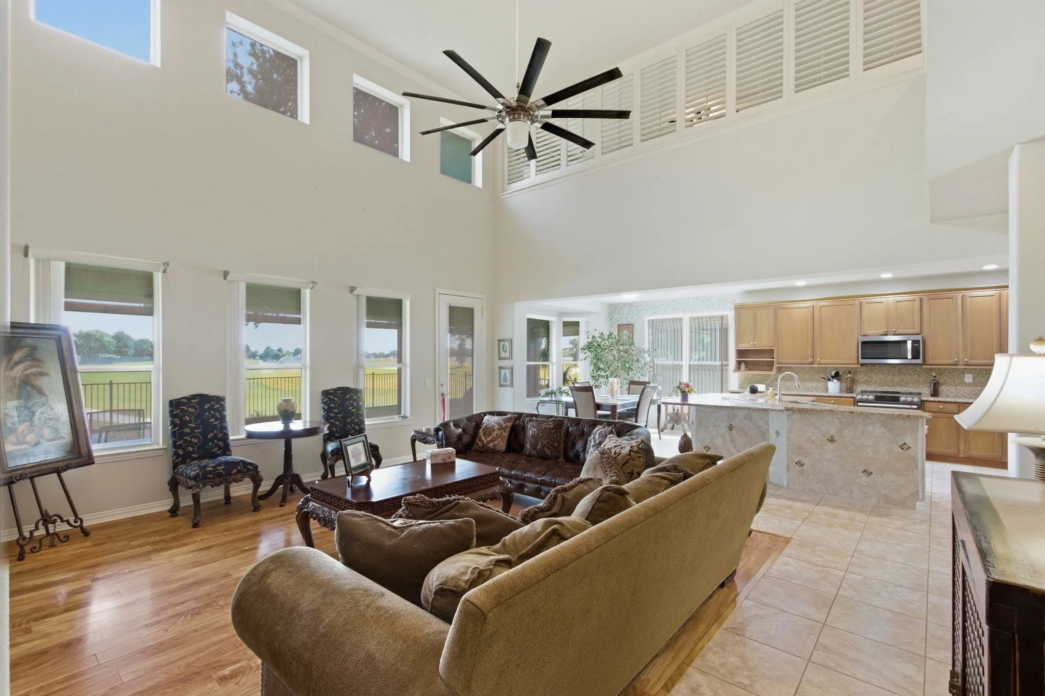 Two-story living area with high ceilings, multiple windows, and a large ceiling fan