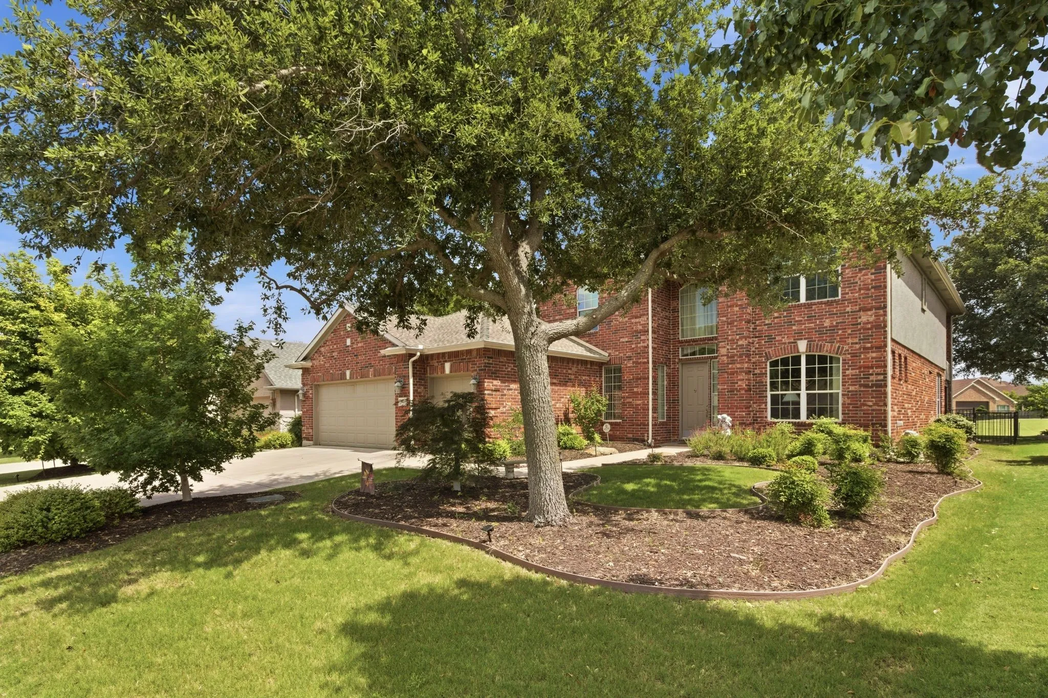 Brick exterior residence featuring a gabled roofline and attached two-car and a half garage. Landscaped with mature trees.
