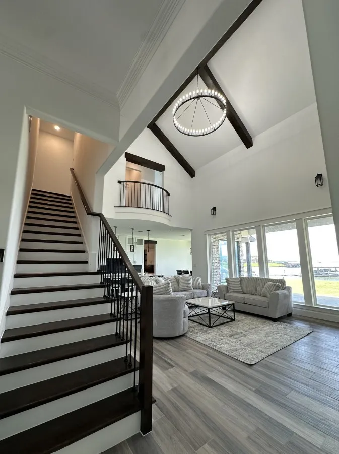 Living area featuring high vaulted ceiling, stairway, a chandelier, beamed ceiling, and wood finished floors