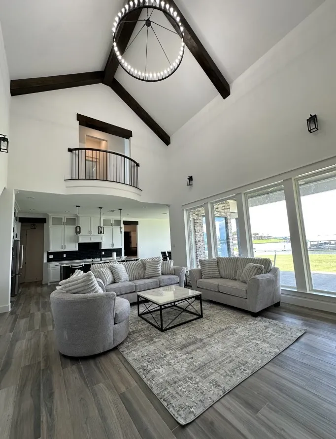 Living room featuring high vaulted ceiling, beamed ceiling, dark wood-type flooring, a chandelier, and plenty of natural light