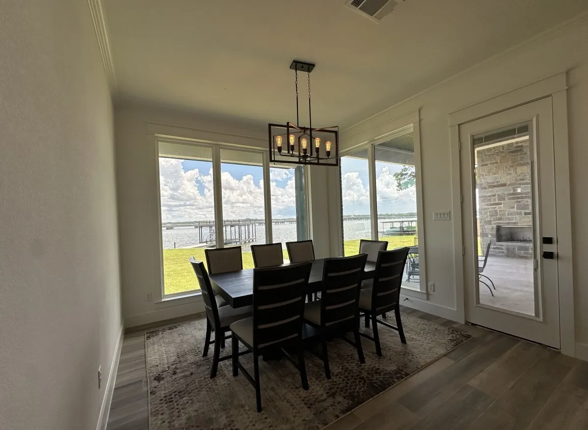 Dining space featuring dark wood finished floors, a chandelier, a water view, healthy amount of natural light, and crown molding