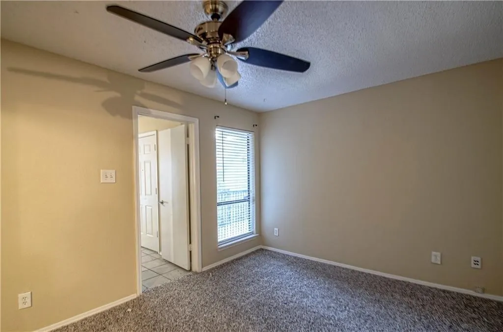 Bedroom with textured carpeting, neutral wall paint, and a ceiling fan with integrated lighting