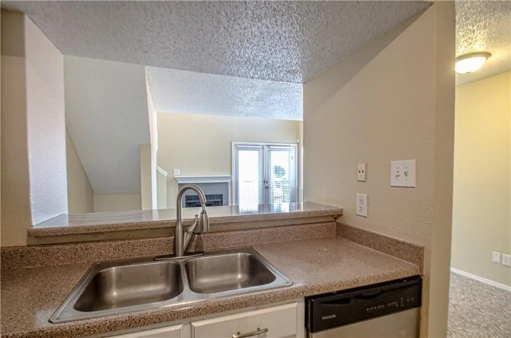 Kitchen sink area featuring a dual-basin stainless steel sink with a modern faucet, set into a speckled countertop