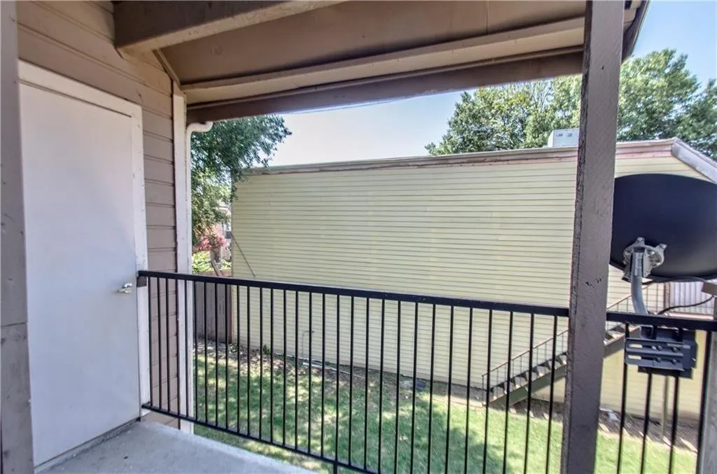 Private exterior balcony with concrete flooring, wood-paneled siding, and a black metal railing