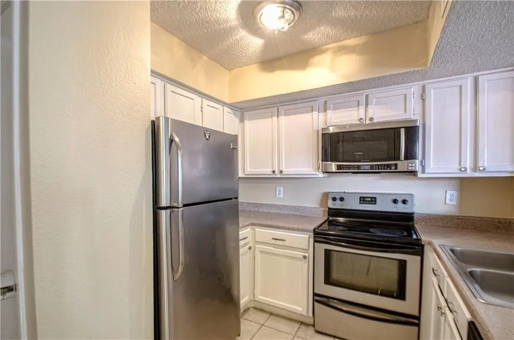 Kitchen featuring white cabinetry, stainless steel appliances, a built-in microwave, and a double basin sink