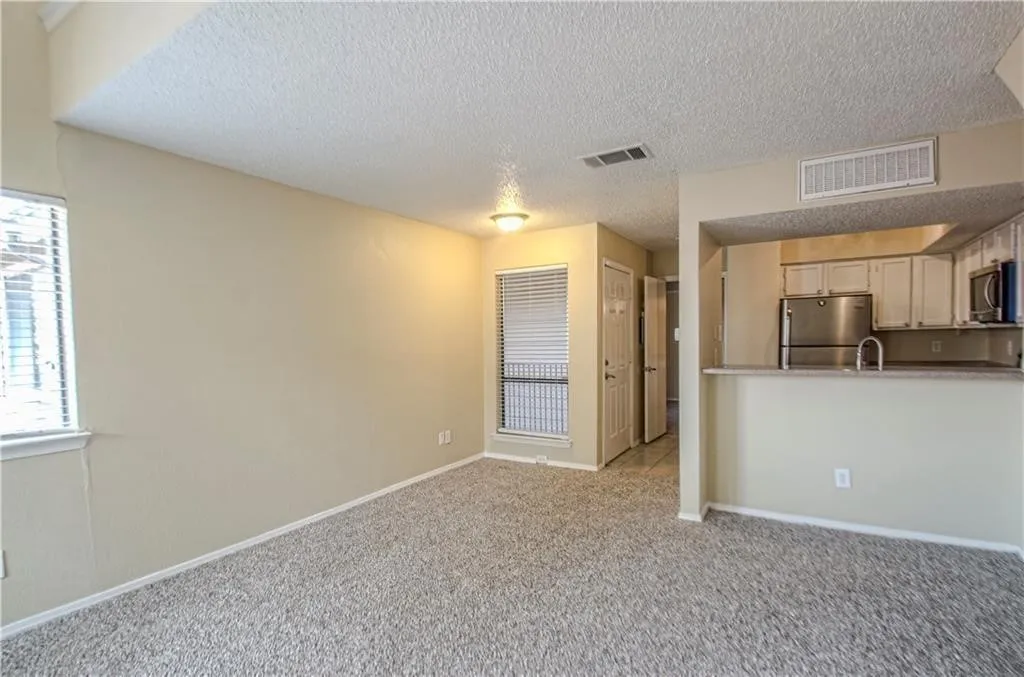 Living area featuring neutral-toned walls, textured ceiling, and patterned carpet flooring