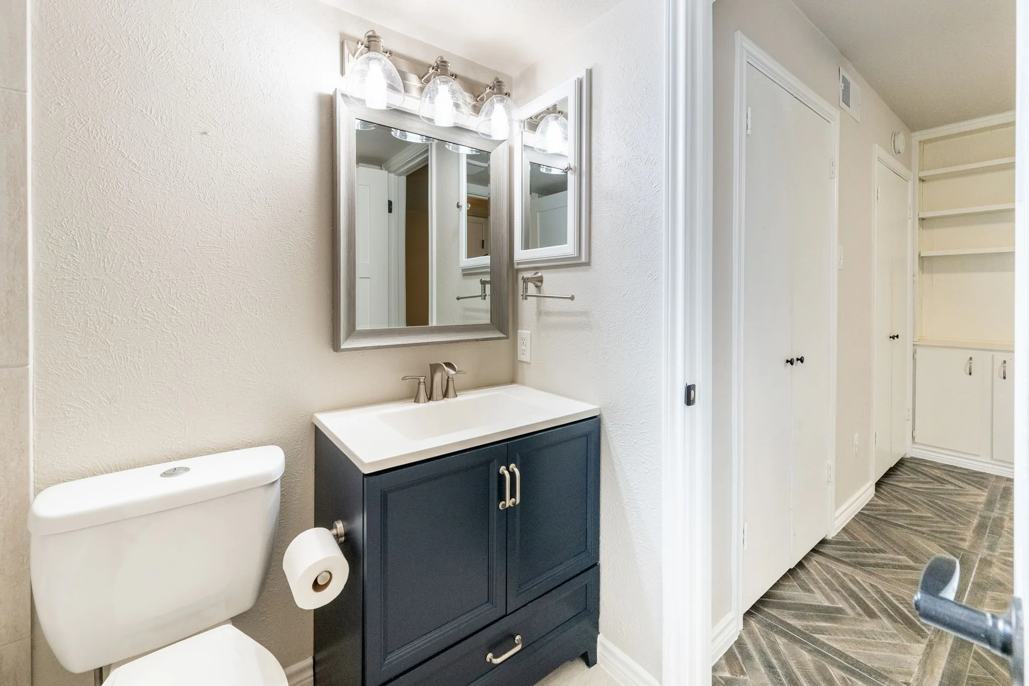 Bathroom featuring a dark blue vanity with a white countertop and integrated sink