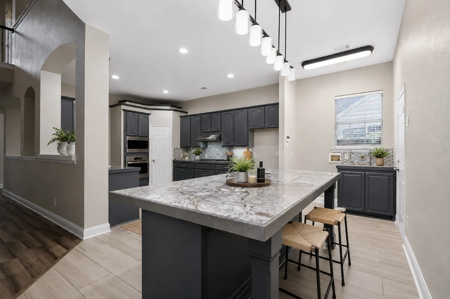 Kitchen featuring a large island with a stone countertop, dark cabinetry, built-in stainless steel oven and microwave  and recessed lighting